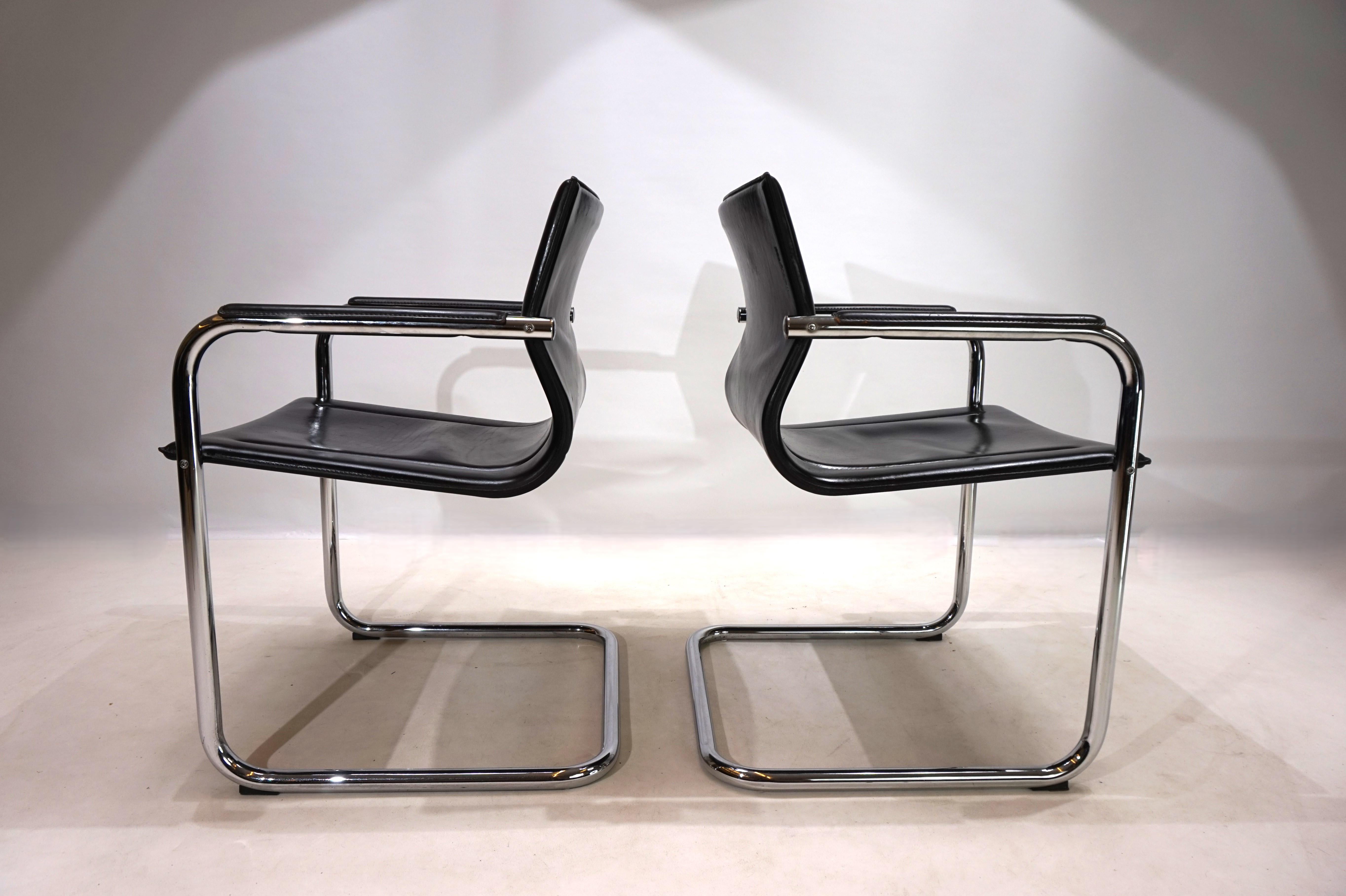 This classic cantilever set of two MG15 chairs in black saddle leather is in first-class condition. The thick leather shows minimal signs of wear, the chrome rods are in very good condition. The armrests are undamaged and the seams are solid. This