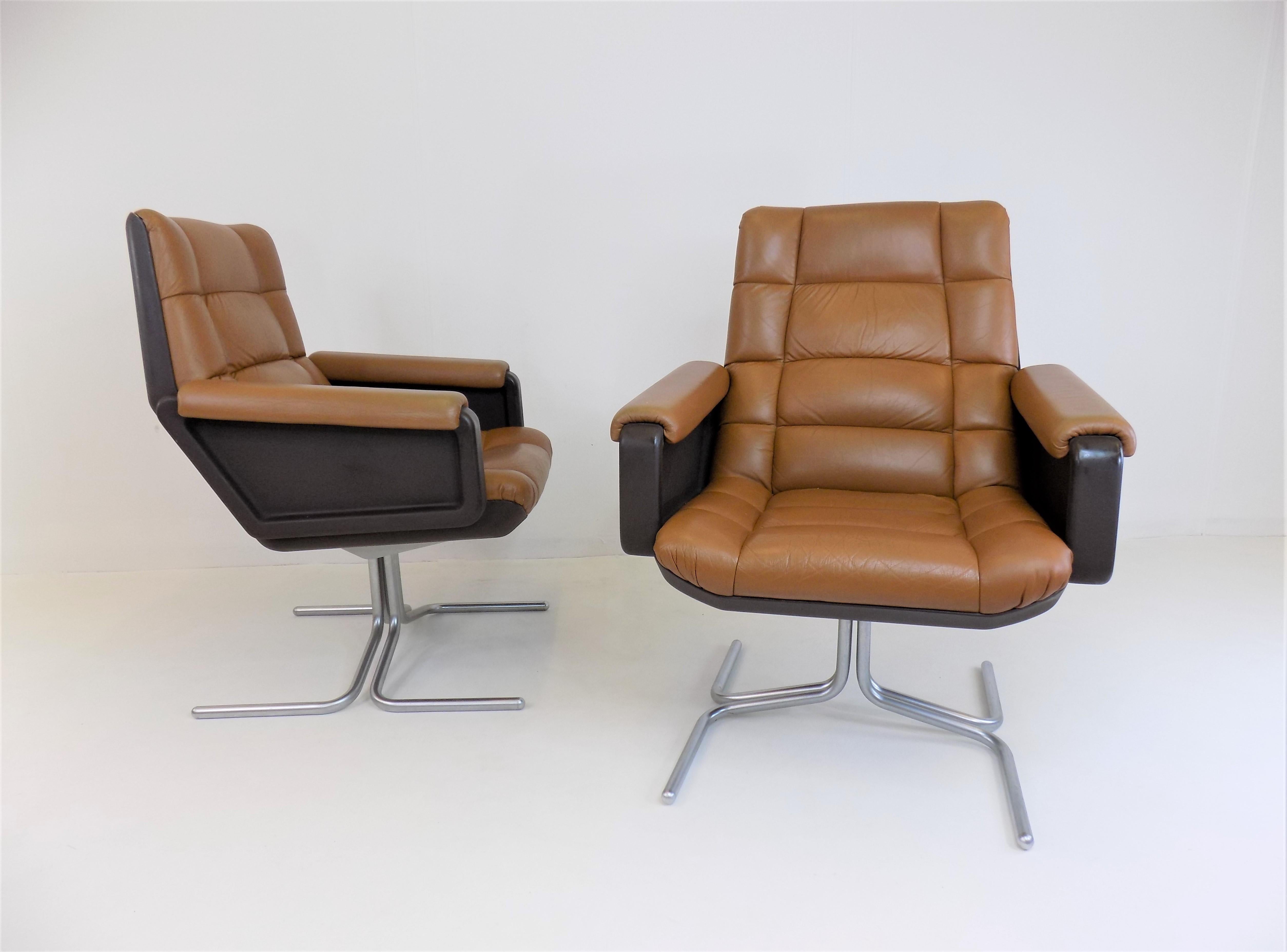 These two Seat 150 leather armchairs are fantastic representatives of the Space Age. The soft, cognac-colored and quilted leather is in very good condition. The brown plastic shells of the backrests show slight signs of wear. The metal base typical