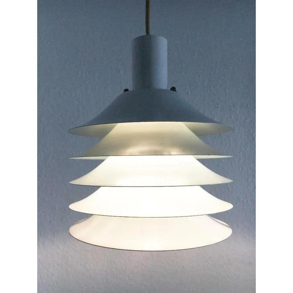 Lampade a sospensione Lamella del produttore danese Lyfa.

Le luci hanno 5 lamelle della stessa dimensione e forma allineate. A seconda della posizione della lampada, la luce viene emessa in modo diverso dalla lampada e conferisce a ogni doga un