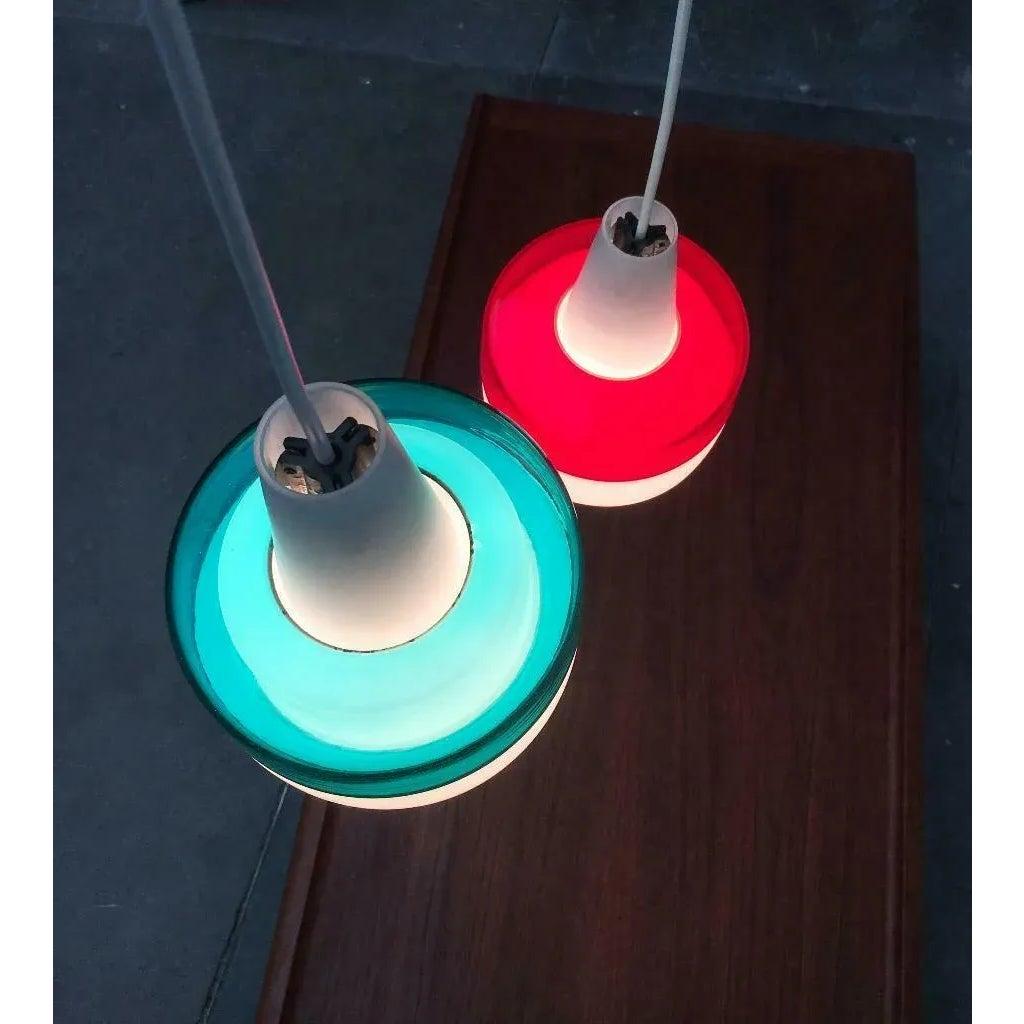 Due pendenti in vetro colorato del rinomato produttore Putzler.

L'intero linguaggio del design sembra piuttosto scandinavo. La forma semplice delle luci è interrotta da un gioco di colori e trasparenze. Il cilindro in vetro colorato e trasparente,