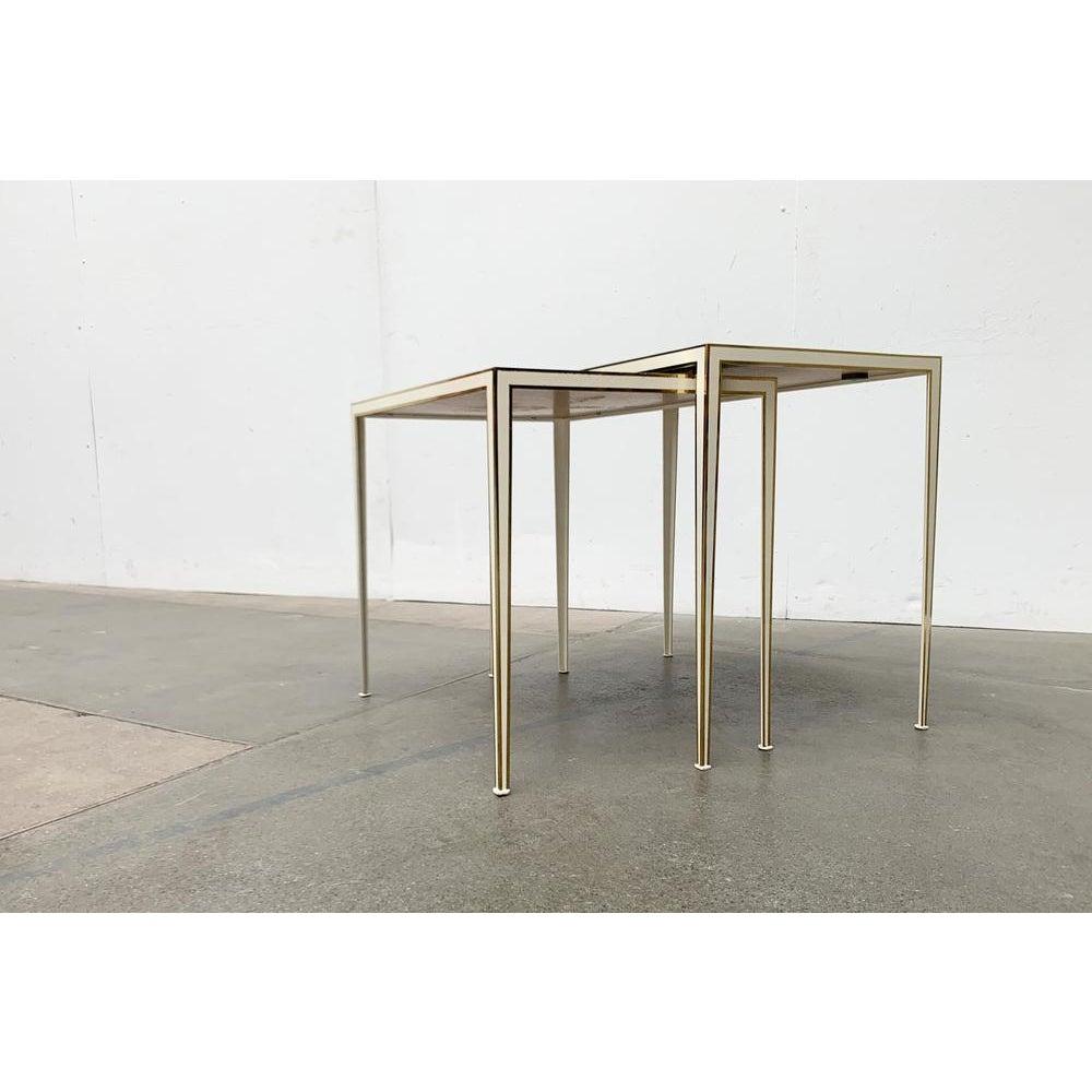 Filigree mid century nestling tables made of brass and mirror glass by the renowned manufacturer united workshops, munich.

The tables consist of a fine frame made of brass with a inserted table surface made of colored mirror glass. The frame forms