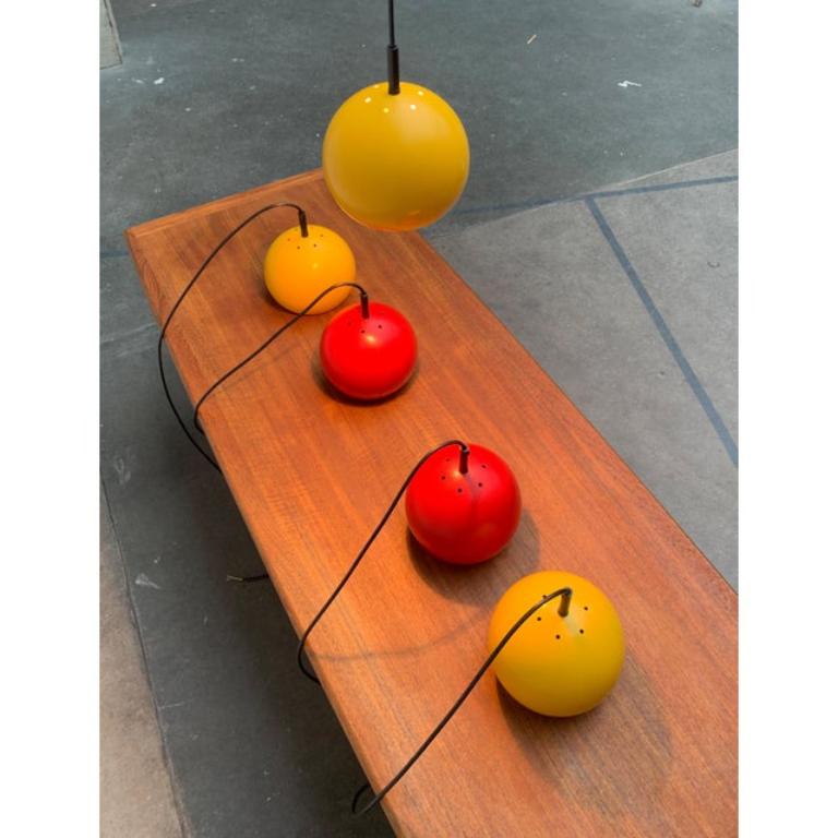 Lampade a sospensione a sfera di metà secolo in rosso e giallo.

Un design classico in un colore speciale. I paralumi formano semplici sfere di metallo, dipinte di rosso o giallo all'esterno e aperte sul fondo. Sulla parte superiore è presente una