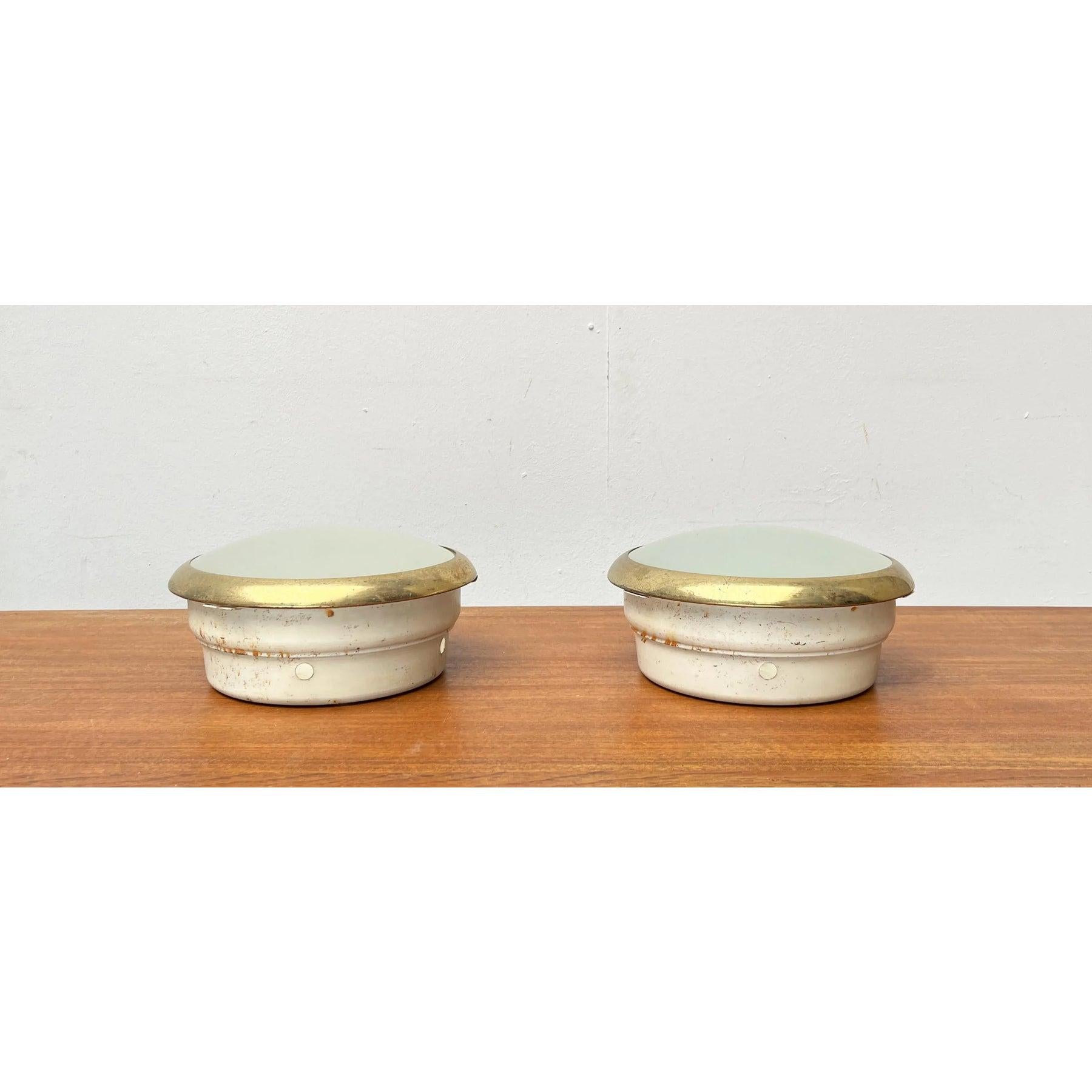 Due plafoniere a incasso di metà secolo.

Plafoniere minimaliste in metallo e vetro. Le luci sono costituite dal vassoio del riflettore bianco e dal diffusore allegato. Una ciotola piatta in vetro satinato, incorniciata in una cornice di ottone,
