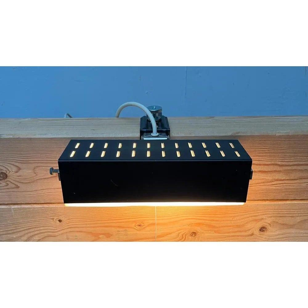 Minimalist Mid Century clamping lights from Leclaire & Schäfer.

A very straight design. The cuboid -shaped body is made of black or dark gray painted metal sheet. As a diffuser, a translucent acrylic pane is inserted as a diffuser. There is a