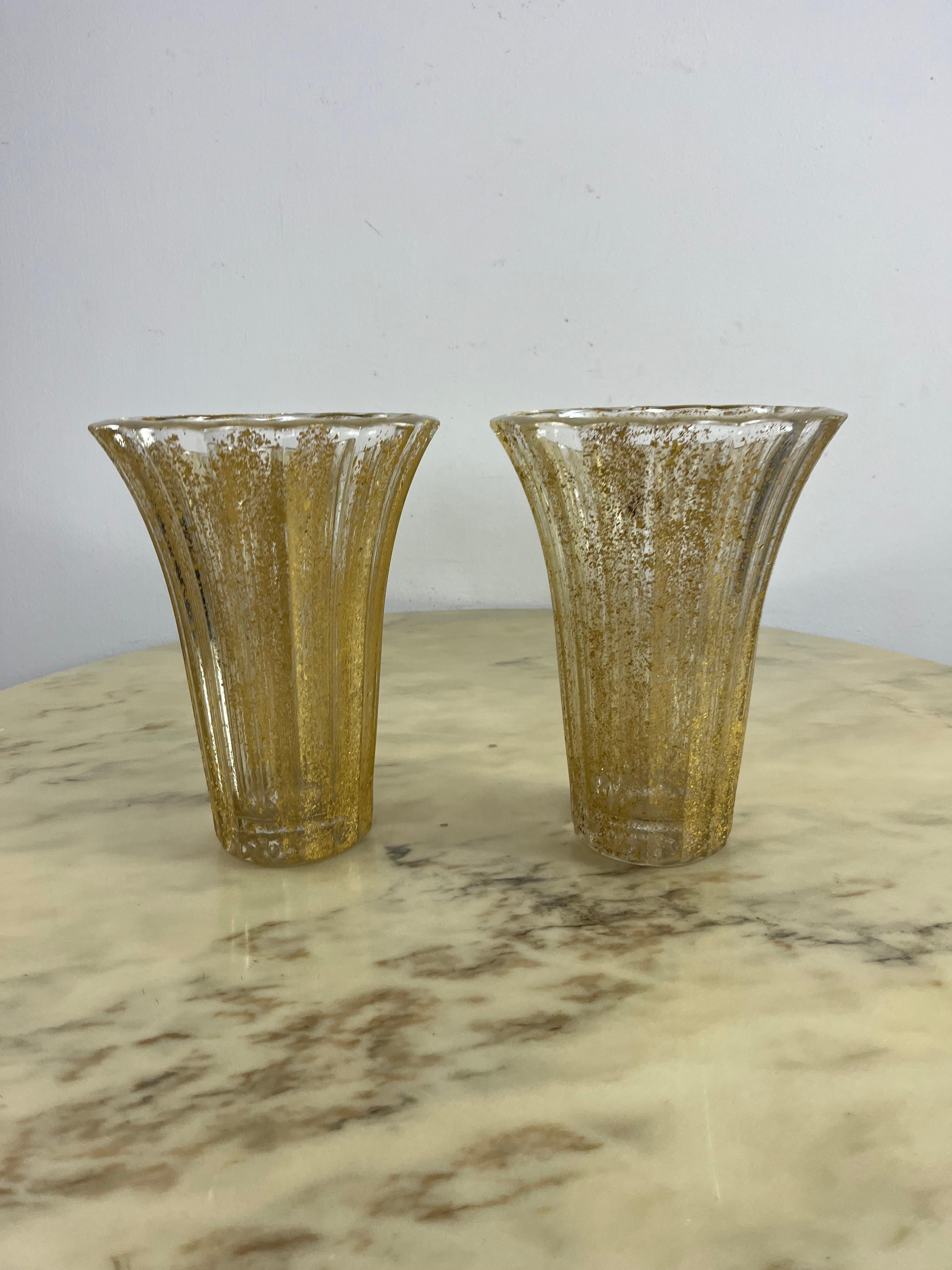 Set di 2 vasi di metà secolo in vetro di Murano foglia oro 1960s
Condit e in buone condizioni, realizzato a mano dai maestri di Murano. All'interno del bicchiere si possono notare piccole bolle d'aria, tipiche della lavorazione artigianale.