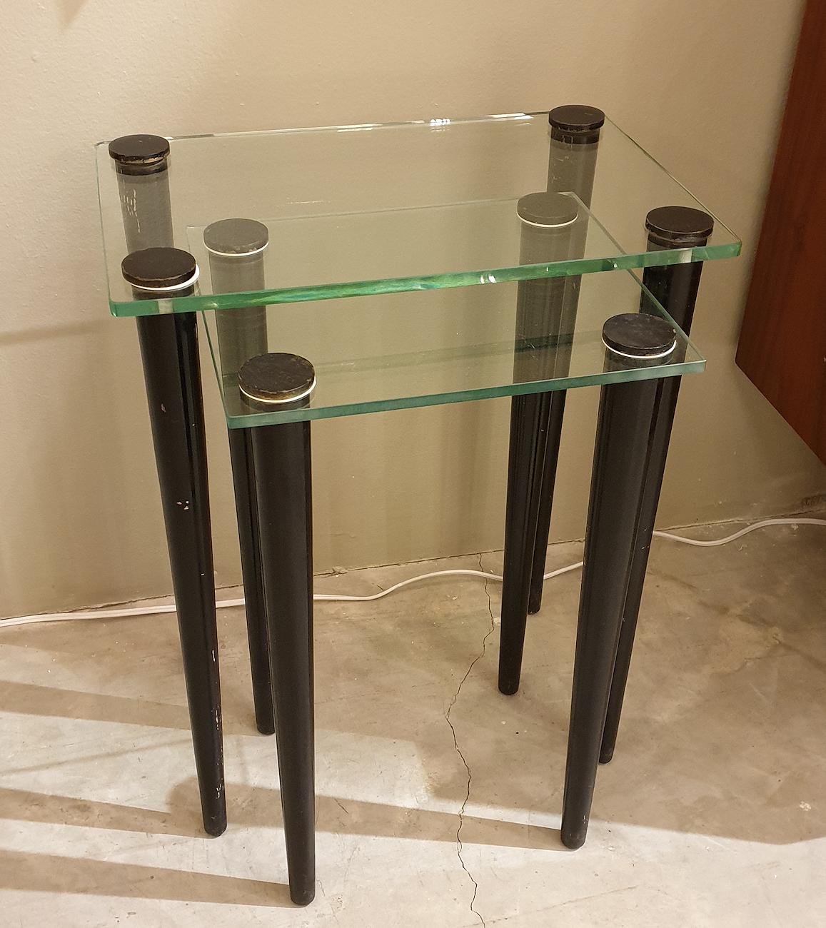 Set of 2 small nesting tables, Mid-Century Modern, Italy, 1960s.
Made of 4 black painted wood legs each, and a clear glass square top.
The elongated legs create a sophisticated design.
Some signs of wear with age on the wood: can be fixed with
