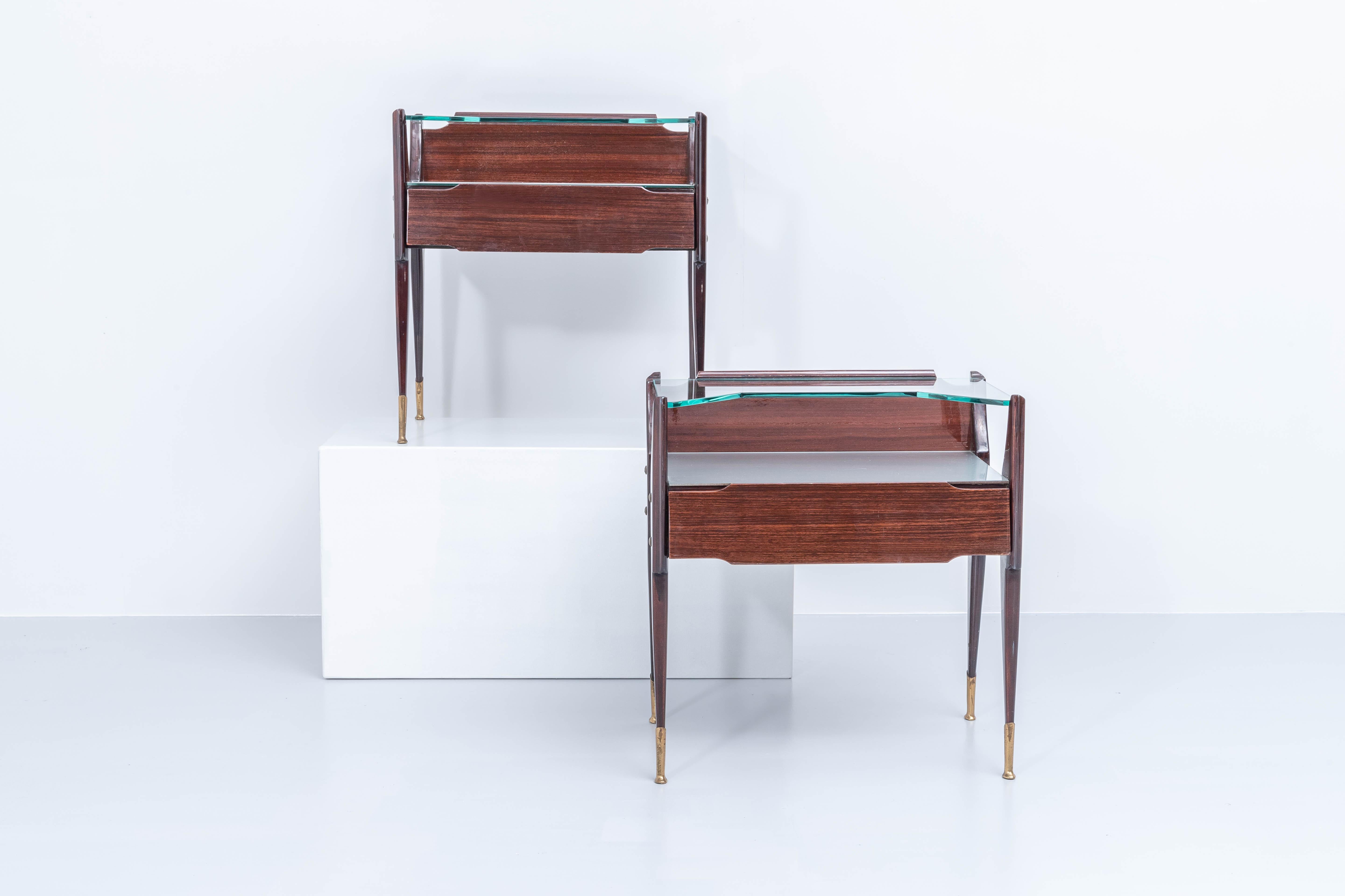 Very elegantly executed set night stands by La permanente mobili Cantù in dark lacquered wood, cut glass and with nicely detailed brass feet. What stands out are the shapes of the nightstands and the materials that were used. There is a double layer