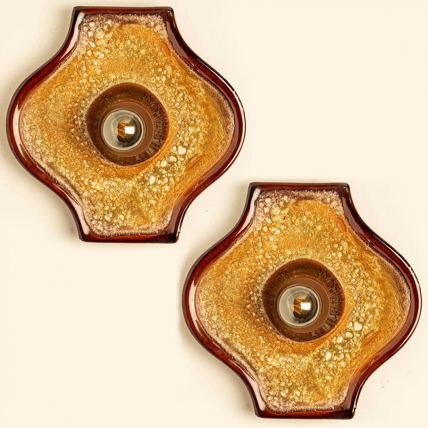 Bellissimo set di due applique ovali in ceramica in stile Fat Lava. Prodotto in Germania intorno agli anni '70.

Lo smalto ha sfumature di colore caldo.

Noi abbiamo utilizzato lampadine trasparenti (vedi immagini), ma anche quelle argentate o
