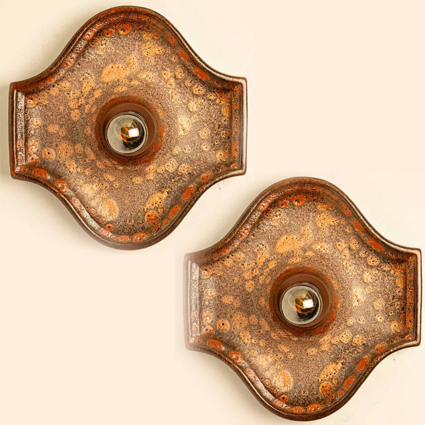 Magnifique ensemble de deux appliques murales ovales en céramique dans le style Fat Lava. Fabriqué en Allemagne dans les années 1970.

La glaçure présente des gradients de couleurs chaudes.

Nous avons utilisé des ampoules transparentes (voir