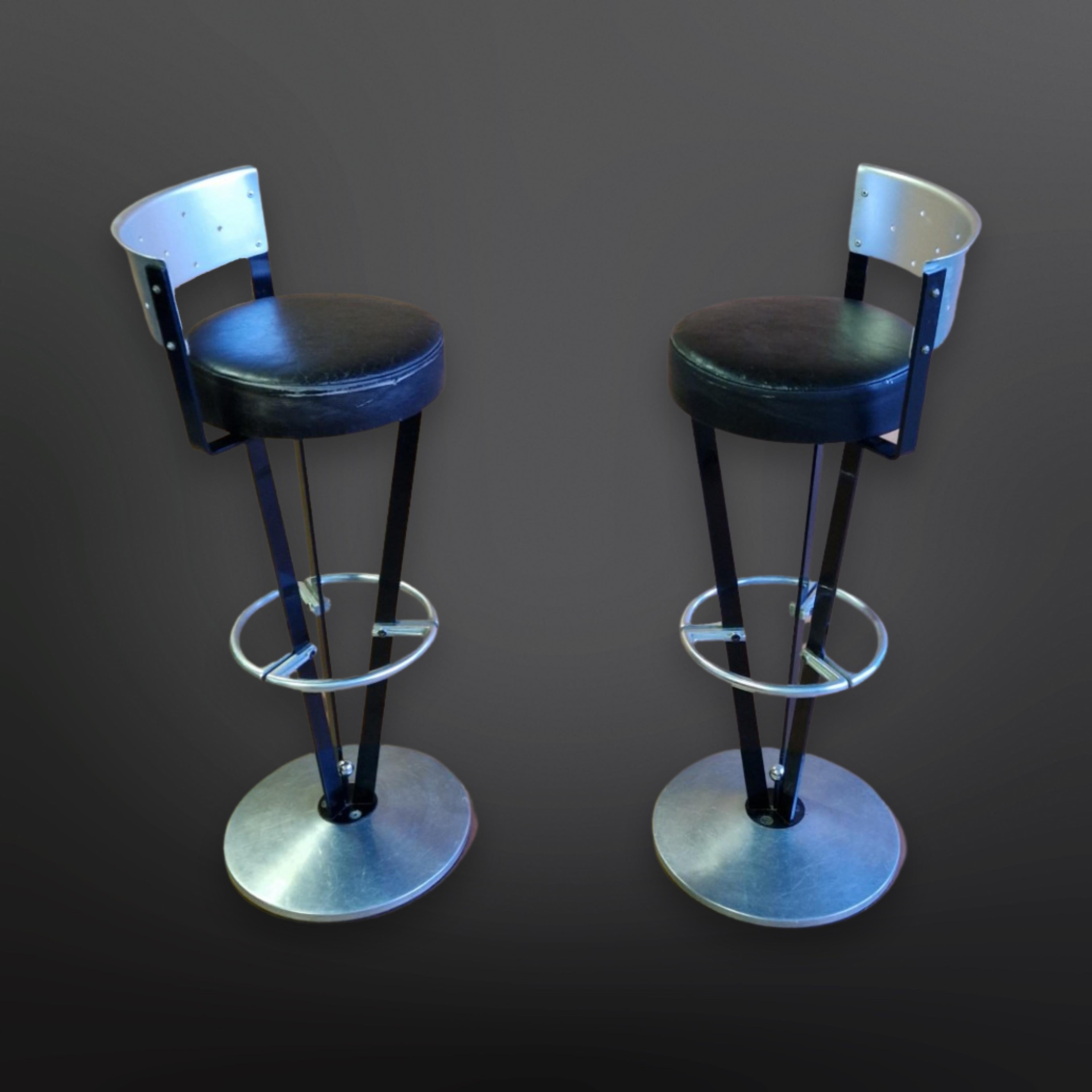 Set of 2 post modern design bar stools. Made from steel, aluminium and leather. The seat height measures 79cm and the height of the backrest is 95cm. Good vintage condition with user marks and a patina consistent with age and use. Designed in the
