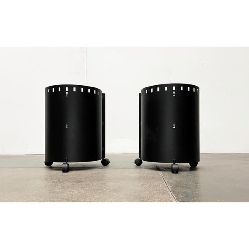Postmodern metal side tables or home bars from D-Tec from the 80s.

The round body is made of heavy steel and is powder-coated black. The front is open. Three wheels make the tables mobile. Each table has two round glass shelves and a lower shelf on