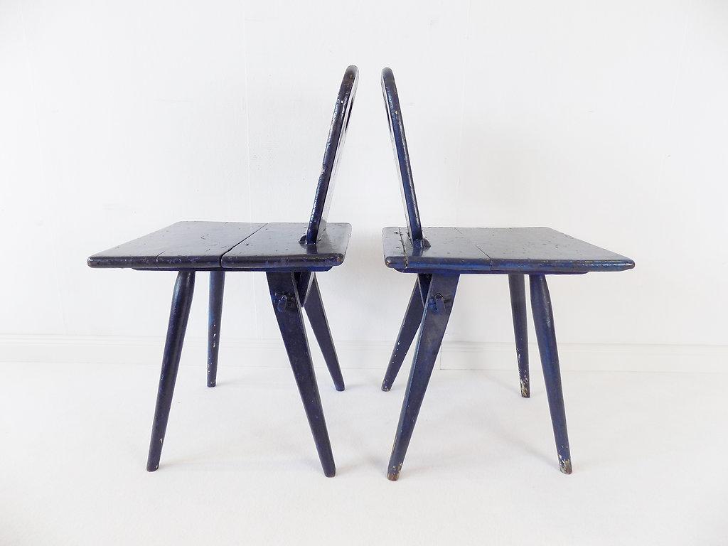 Ces deux chaises de cuisine en bois primitif et très solide ont un charme très particulier. Peints plusieurs fois au fil du temps, ils présentent un grand jeu de couleurs en bleu et paraissent vieillis avec dignité grâce aux signes d'utilisation.
