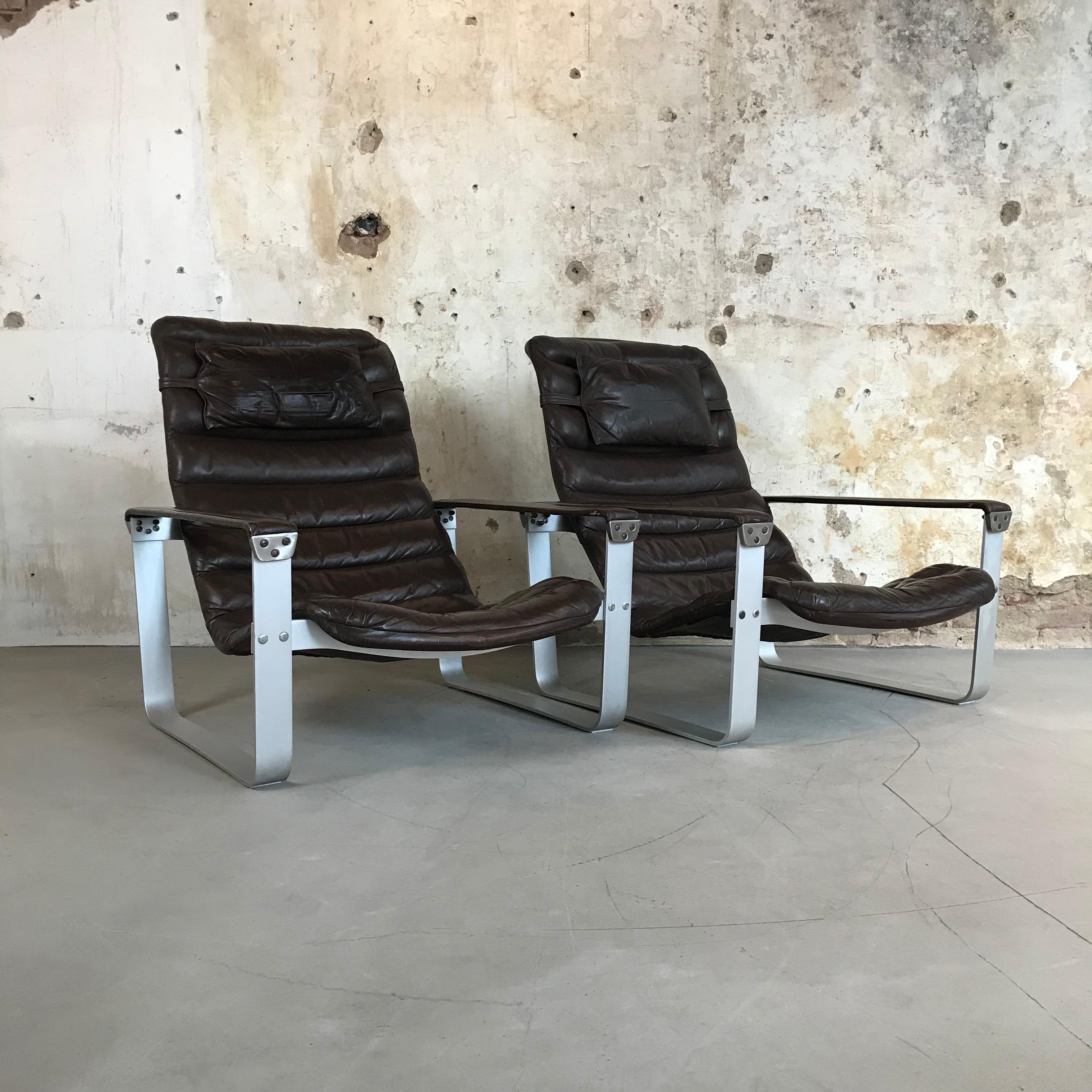 Very nice set of two comfortable low 'Pulkka' Lounge Chairs designed in 1968 by Ilmari Lappalainen and manufactured by Asko, Finland (founded in 1918). 

This chair has an anodized aluminium frame and a dark brown leather upholstered seat with