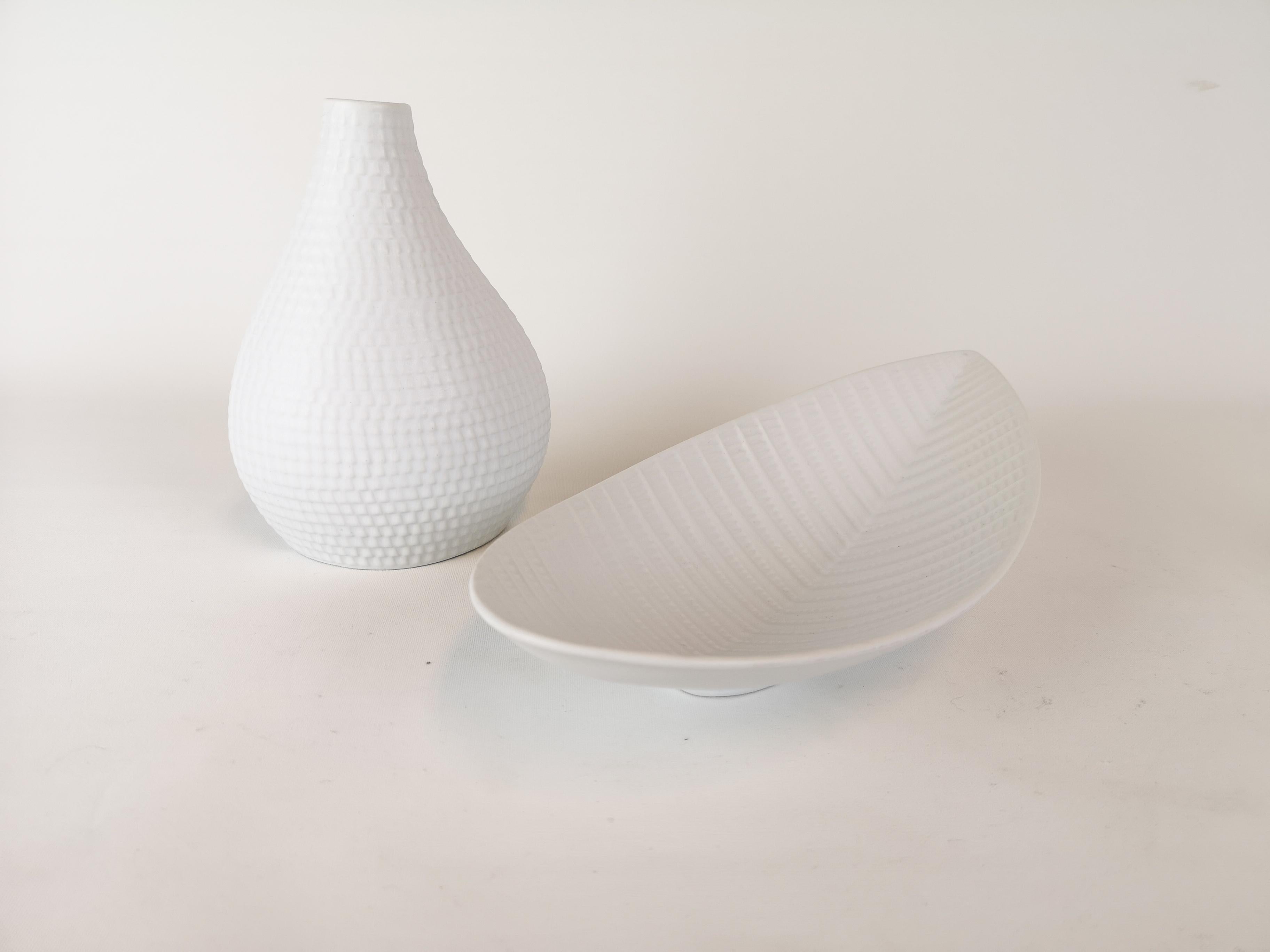 This set of 2 white glazed vase and bowl was produced in Sweden at Gustavsbergs Porcelain Factory. And they were designed by Stig Lindberg. They were meant to look like the skin from a reptile.

Good condition.

Dimensions: The vase H 19 W 14 D 8 cm