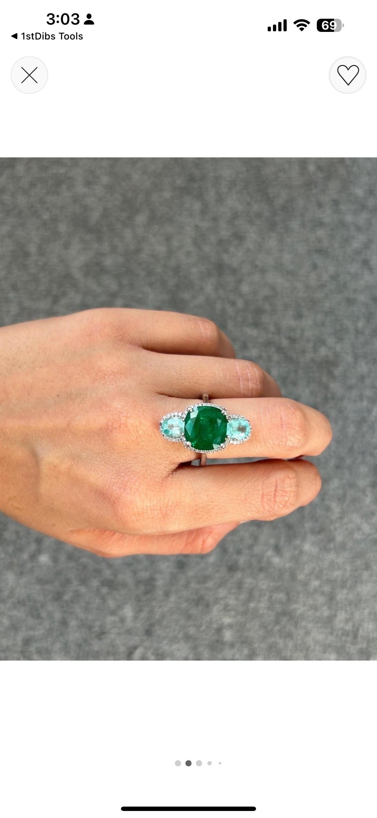 A very uniquely designed certified natural 4.08 carat Zambian Emerald pear shaped, with 0.61 carats of pear shaped White Diamonds, surrounded with Diamonds and Tsavorites - giving it an art-deco look. The center stone is an ideal vivid green color,
