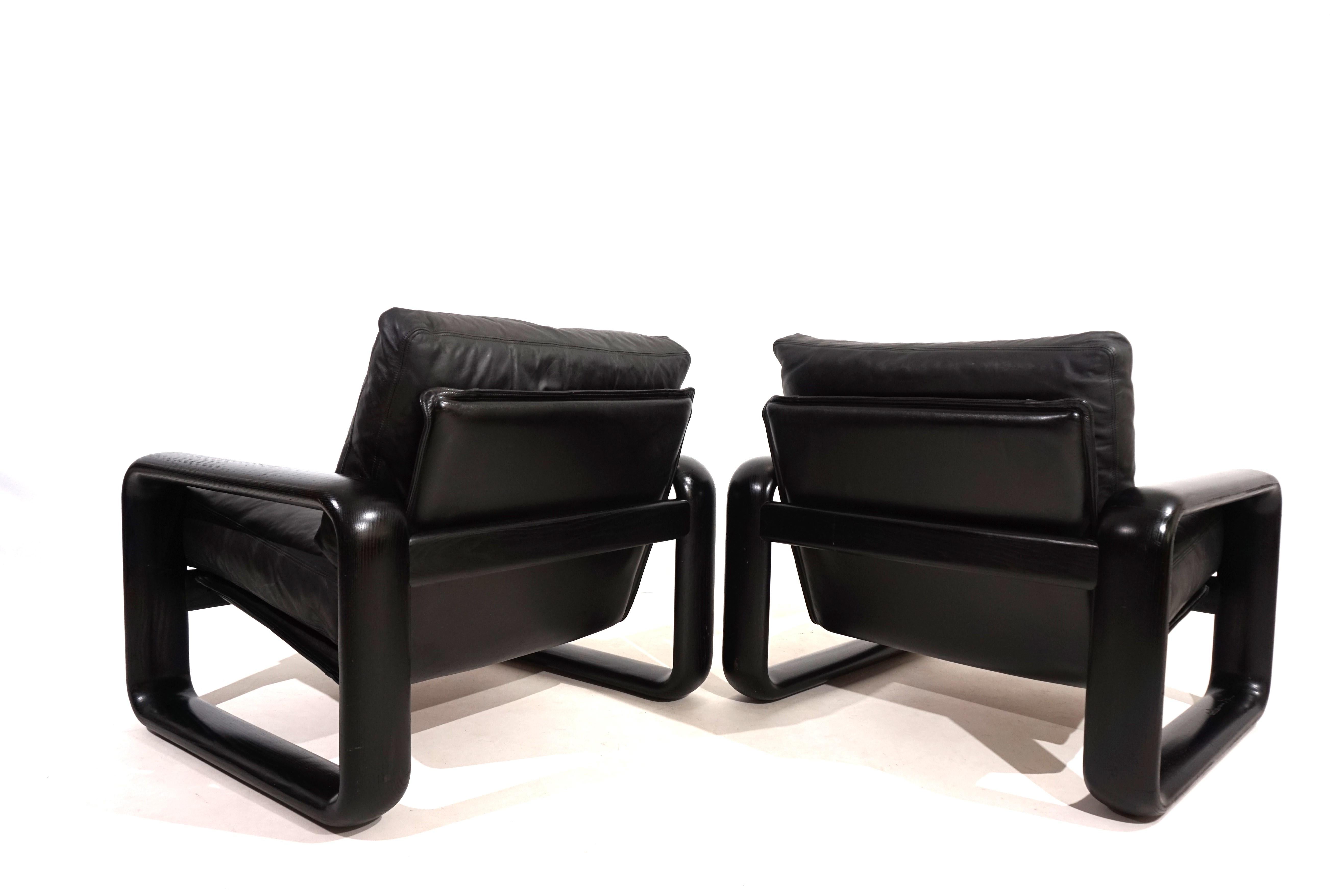 Two Hombre leather armchairs in the popular design, black wooden frame and black leather in very good condition. The leather of the cushions and backrest shows hardly any signs of wear and is soft and supple. The solid wooden backrests show slight