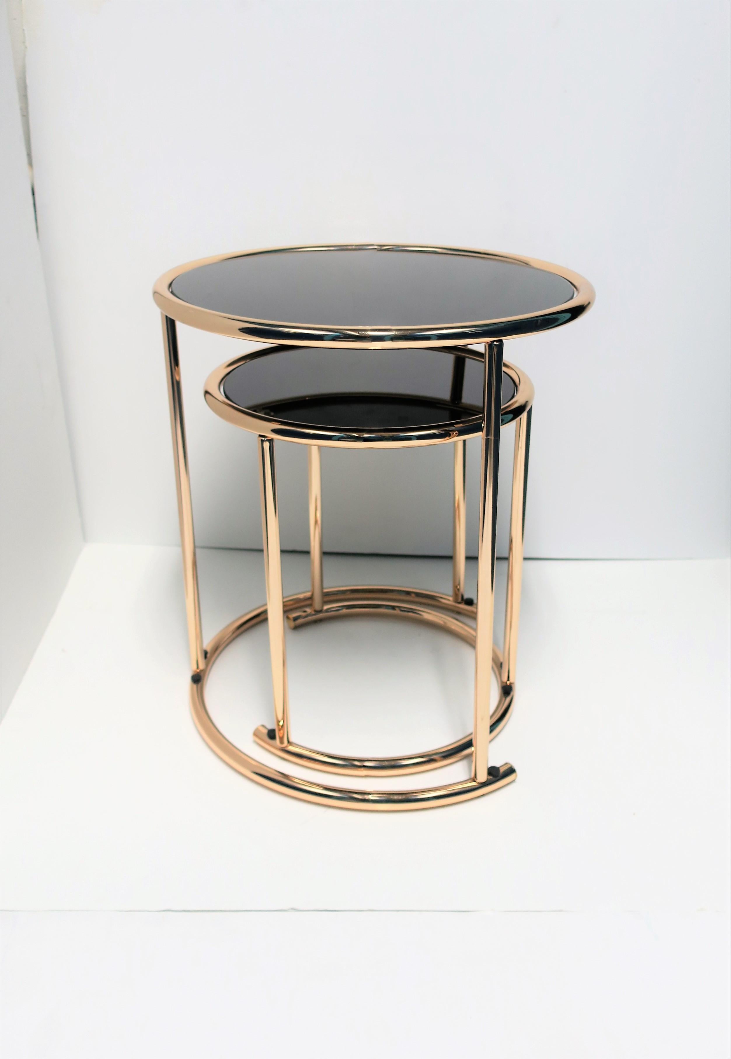 A chic set of 2 Modern style round side/nesting tables with a tubular frame and black mirrored glass tops. Table frames are a brass/rose gold hue plated metal; a great combination with the black mirrored glass tops as show in images. 

Measurements: