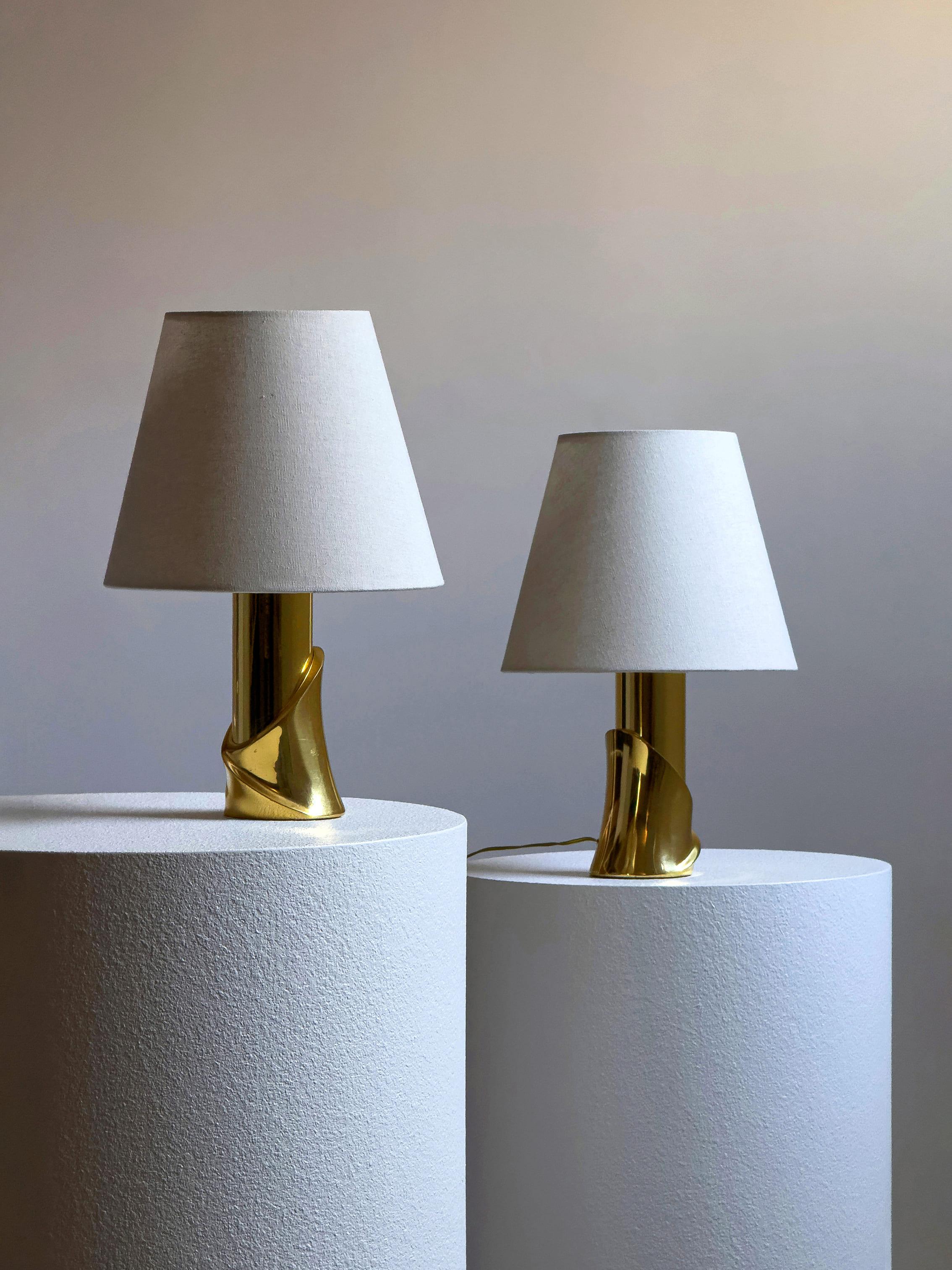 Elegante paire de table en laiton fabriquée en Italie dans les années 1960-1970. Chaque lampe est dotée d'une base sculpturale en laiton poli au design raffiné et torsadé et d'un abat-jour en tissu léger qui émet une lueur chaude et ambiante.

Les