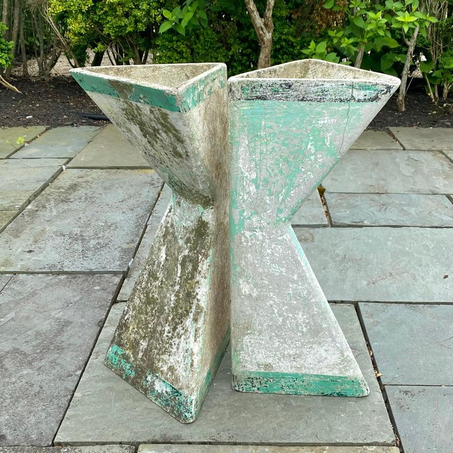 Set of 2 sculptural standing triangular concrete planters by Swiss Architect Willy Guhl. Can be placed upside down or right side. up. Beautiful patina with worn green and white paint revealing cement underneath, mottled with lichen throughout.
