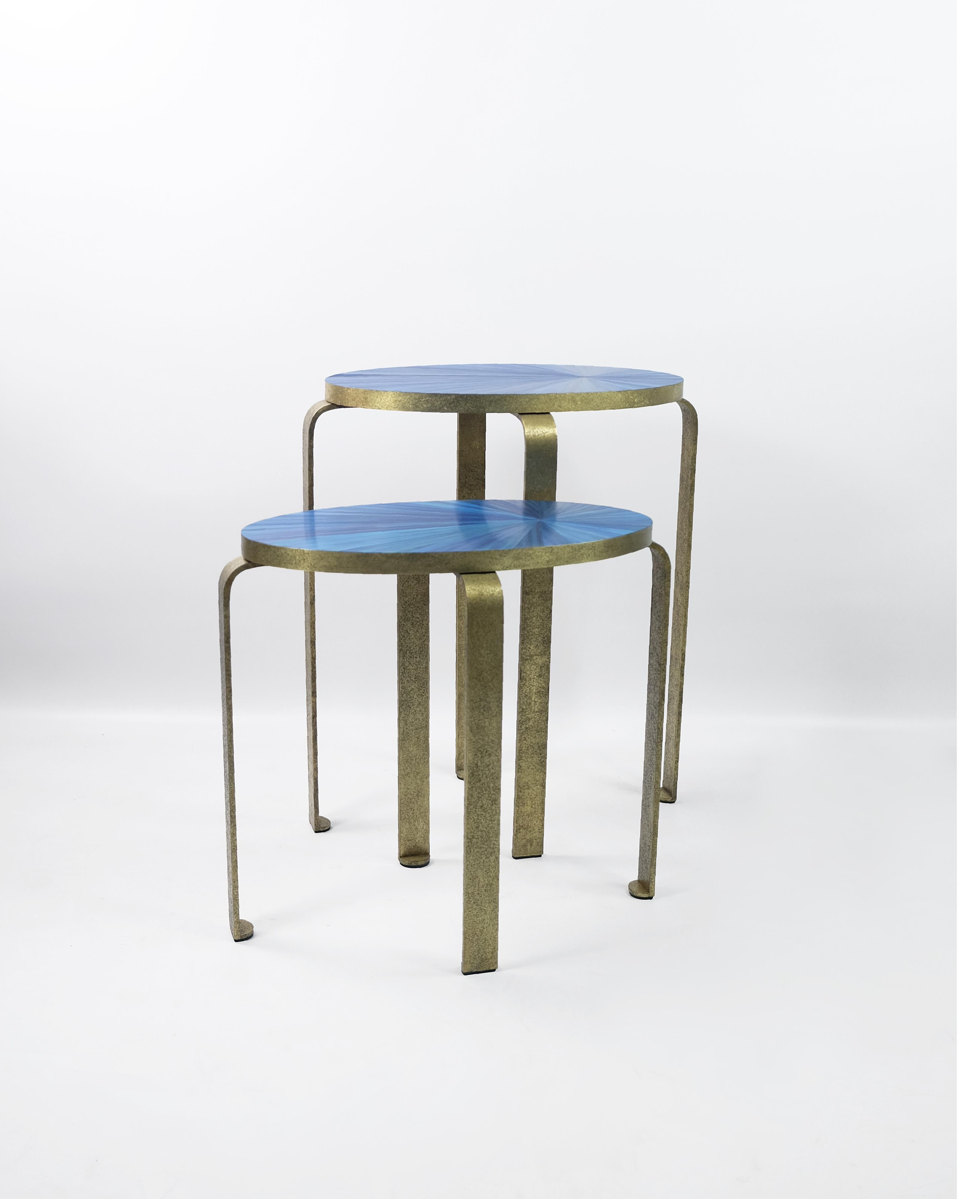 L'ensemble de deux tables d'appoint est en laiton texturé avec un plateau ovale en marqueterie de paille bleue.
Le laiton a été martelé à la main pour donner un aspect irrégulier et artistique à la finition.
Le bleu de la paille s'accorde