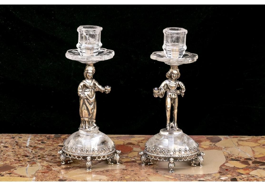 Innalzate su basi ovali con quattro piedi montati in argento, formate da leoni in piedi.  Il piede in cristallo di rocca montato in argento sostiene dei piedistalli a forma di figura che a loro volta sostengono delle coppette per la cera a forma di