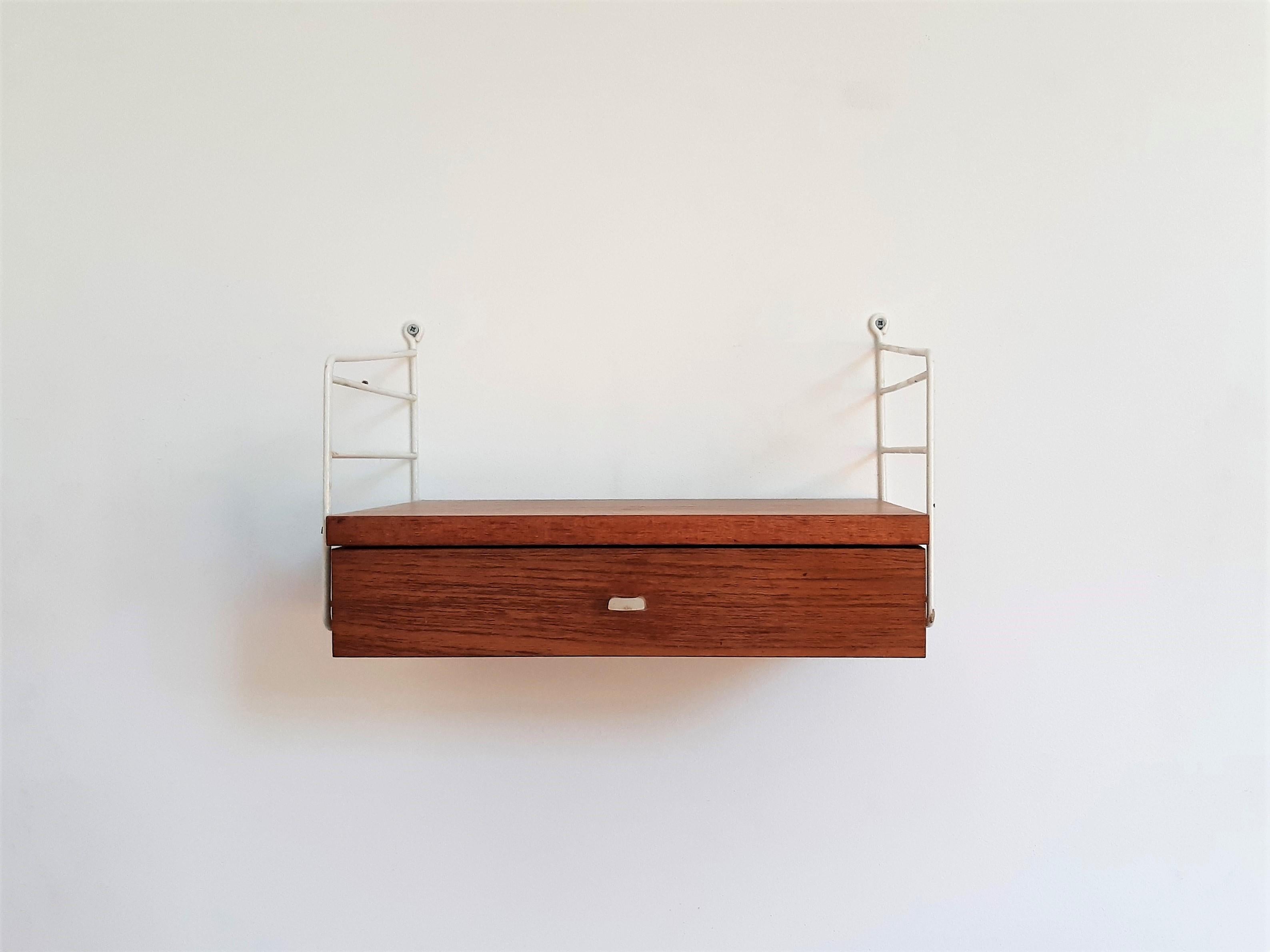 This charming and rare set of 2 wall mounted drawer units was designed by Nisse Strinning and made for String AB in the 1950's/1960's in Sweden. This is an original set of 2 and each unit consists out of 2 white coated metal uprights, holding 1 teak