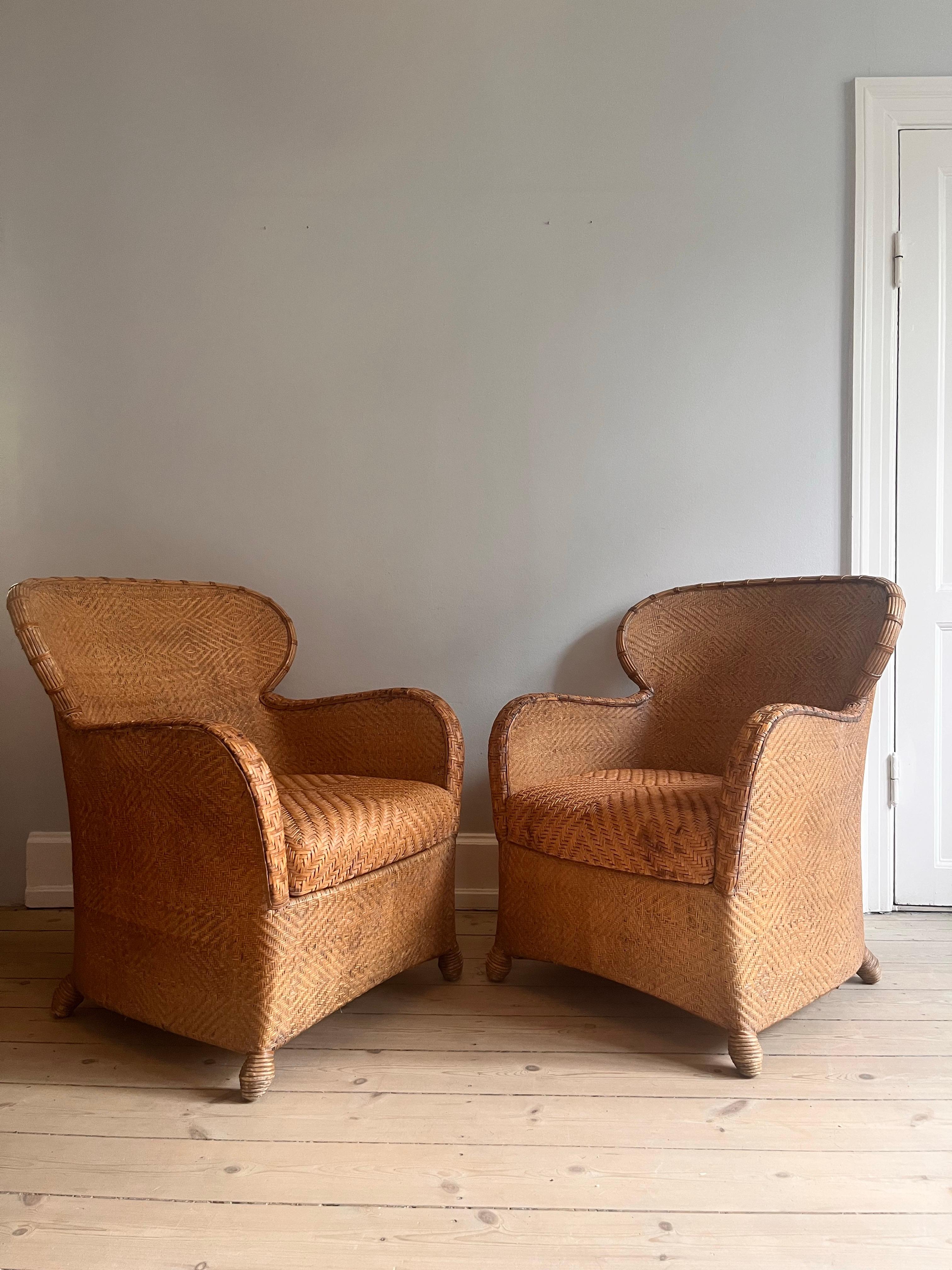 Set of two Søren Lund chairs in caning and leather. 

The chairs are from the 1960s and in great condition. 

Armrests and the large, soft seat cushions are in detailed leather braid - the rest of the chair in caning. 

Both chairs have a sculptural