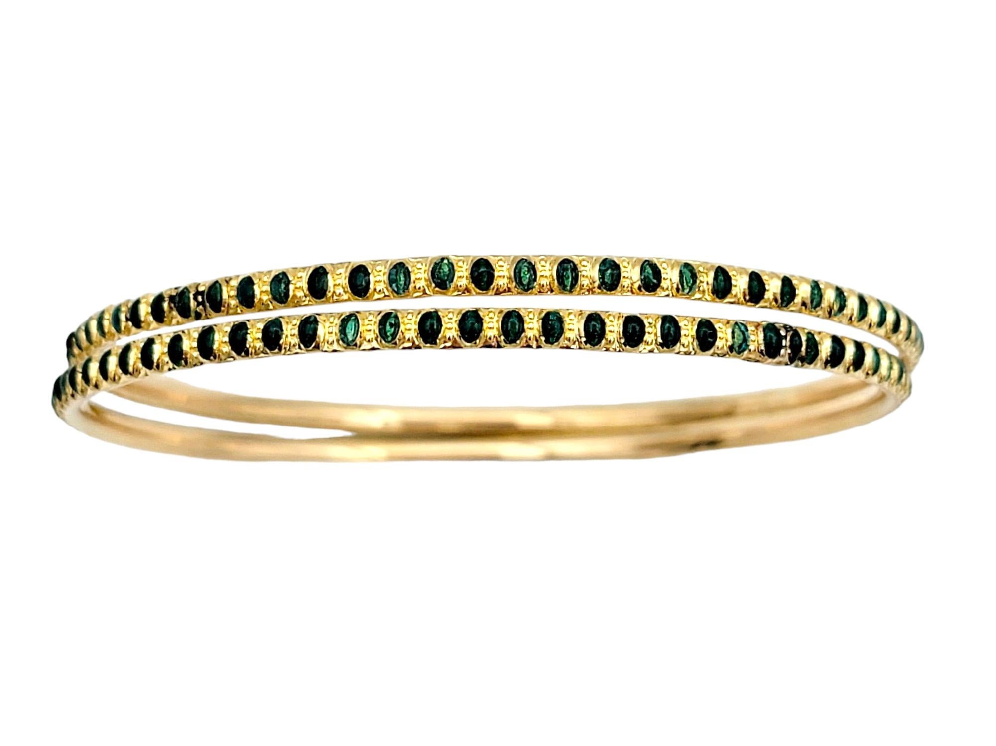 Introducing a stunning set of two narrow stacking bangle bracelets crafted in luxurious 22 karat yellow gold. These identical pieces are adorned with a mesmerizing dark green enamel dotted design that spans the entire length of the bracelets, adding