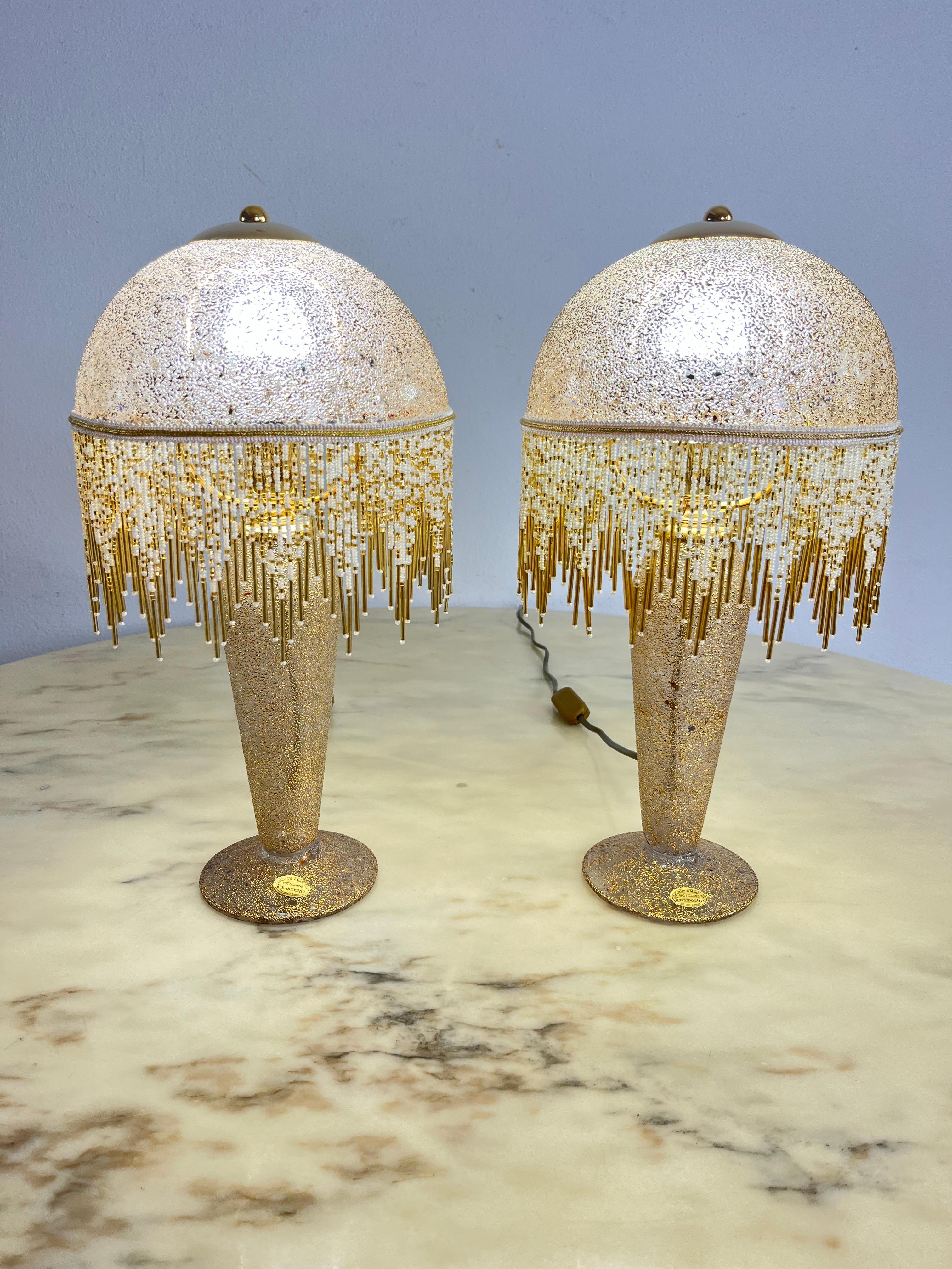Ensemble de 2 lampes de table en verre soufflé à la bouche et décoré à la main d'or pur Années 1980
Entièrement en verre, y compris les abat-jour. Frange avec microperles.
Intact et en excellent état. Lampes E14.