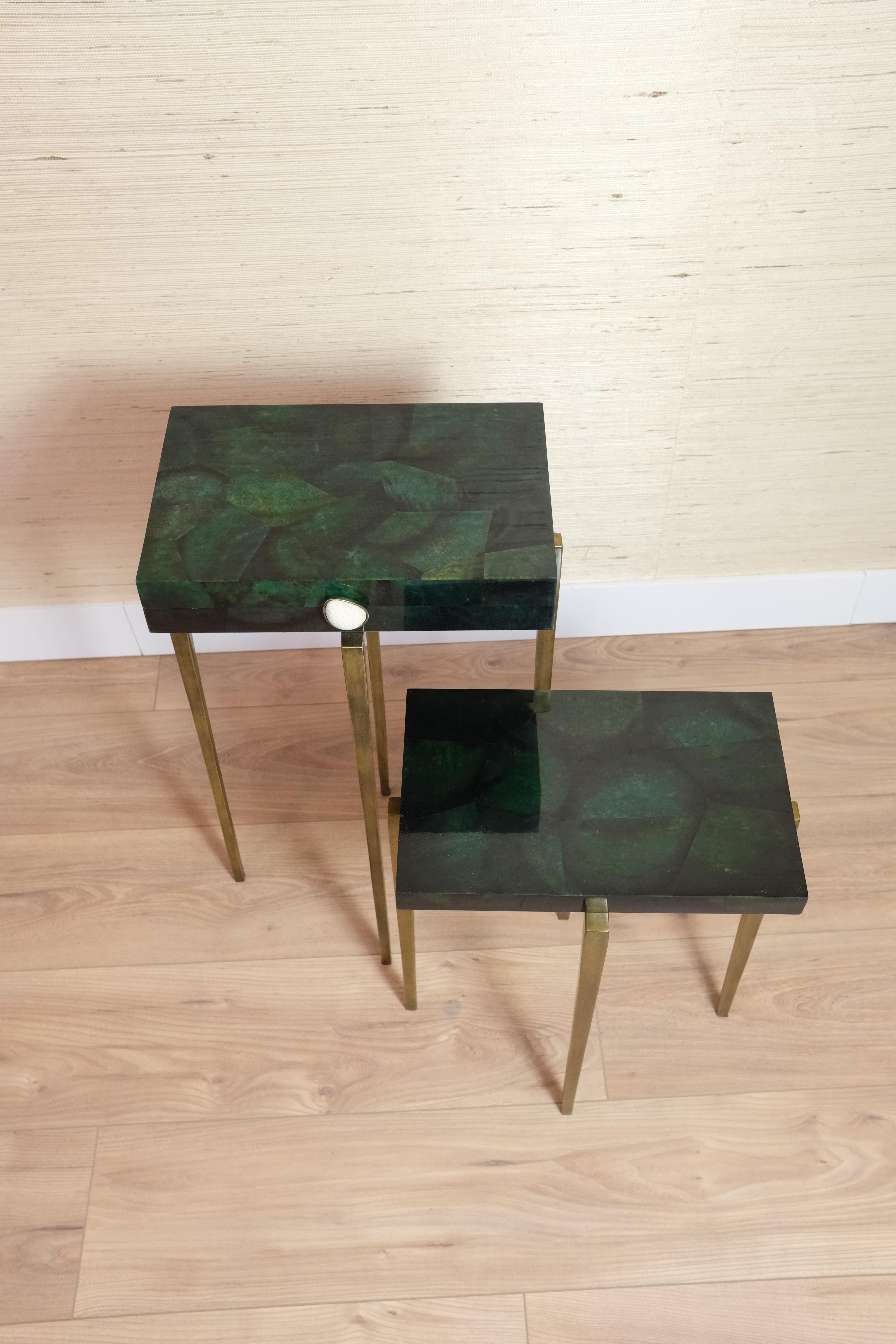 This set of tables is made of polished green shell marquetry.

One of the tables is a box with an hinged lid. It has a brass and shagreen handle. 
The interior is made of black suede.

The metal feet have an antique brass patina.

The tables are