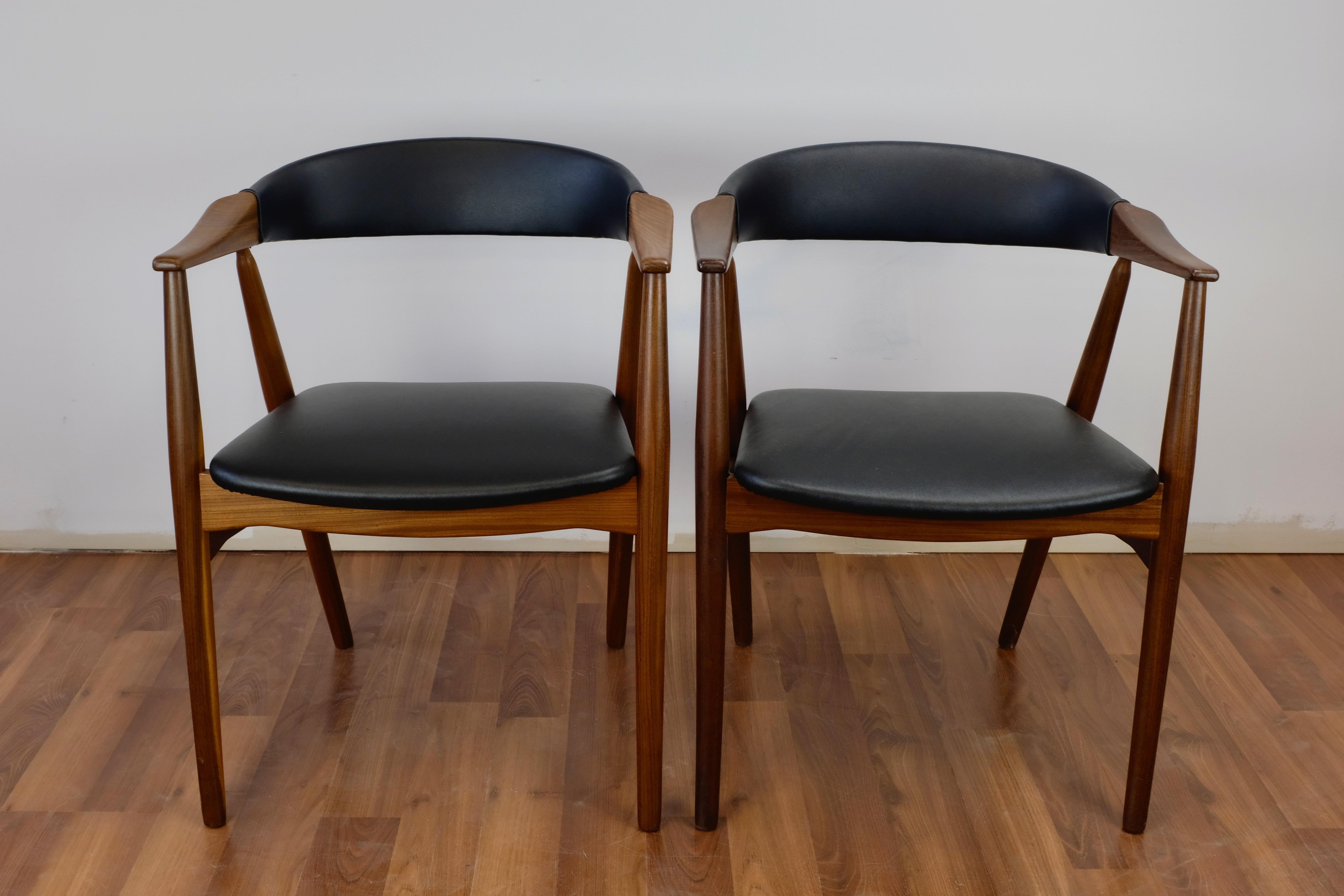 Set of two teak armchairs made in Denmark by Farstrup Stolefabrik with upholstered seats and backs.

The chairs have been fully refinished and reupholstered with black leatherette. One of the chairs has a metal bracket where the arm meets the