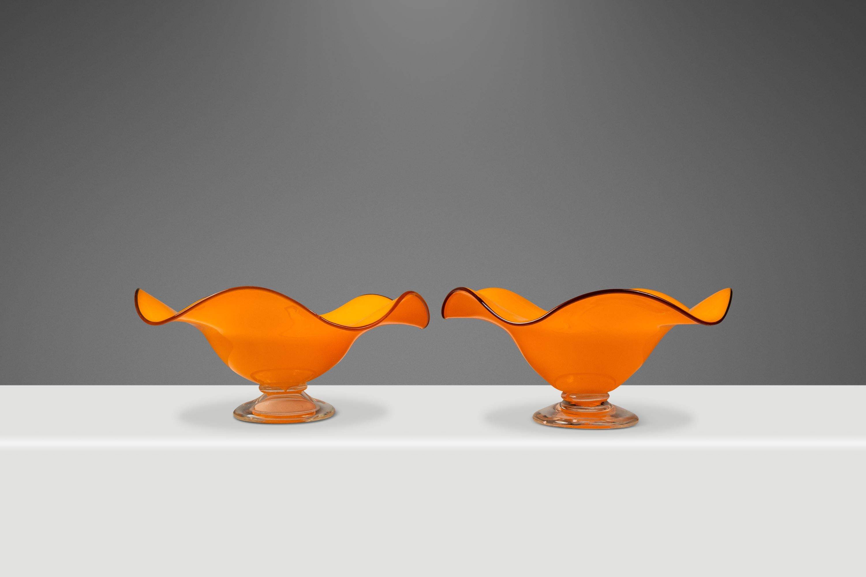 This stunning set of two Teleflora blown art glass serving bowls, crafted in the USA during the 1970s, captures the vibrant spirit of mid-century design. Featuring bold orange hues that transition into clear pedestal bases, these handcrafted pieces