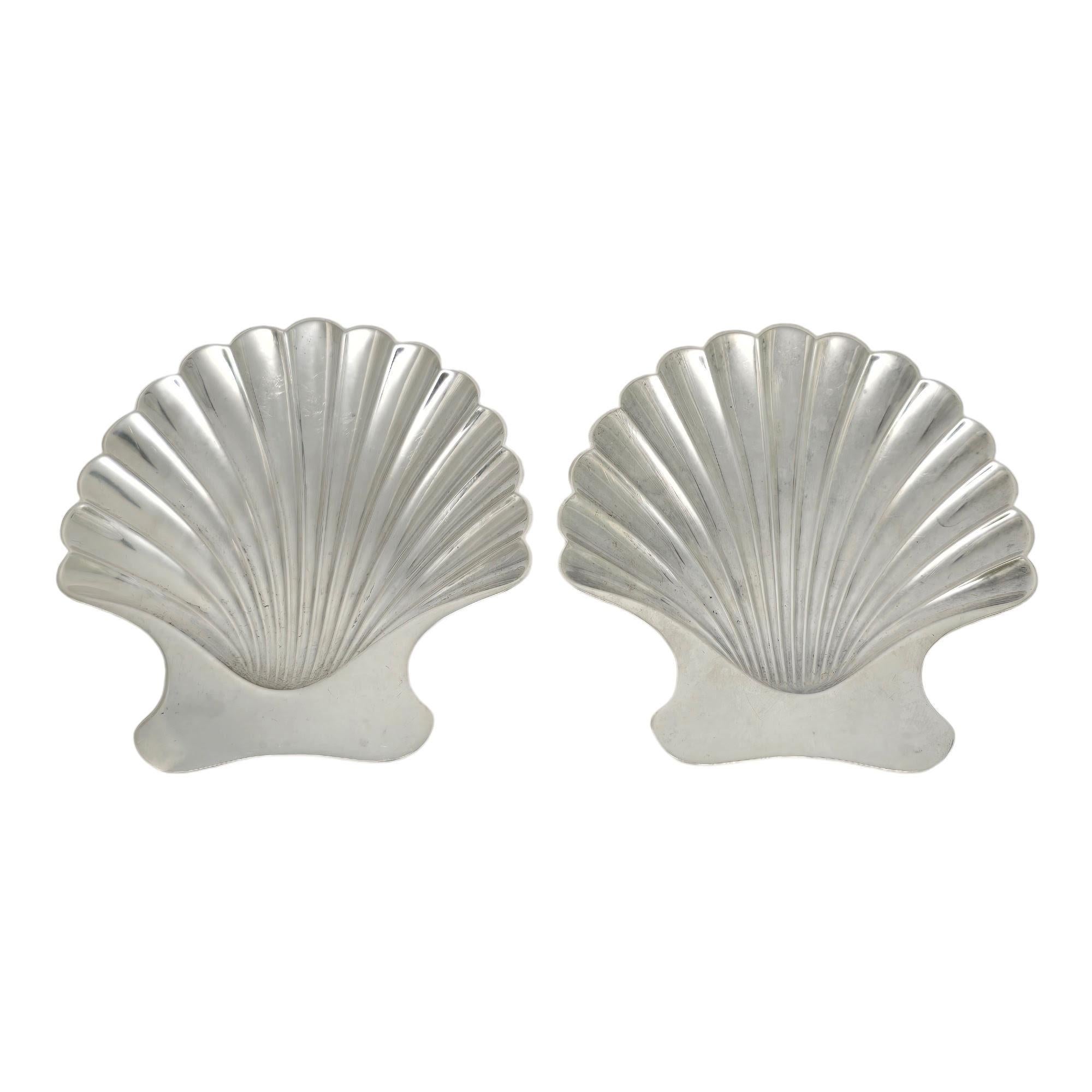 Set of 2 sterling silver scallop shell dishes with pouches by Tiffany & Co, pattern # 22369.

2 small bowls in the shape of a scallop shell with 2 ball feet underneath. Hallmarks date these pieces to manufacture under the directorship of Louis