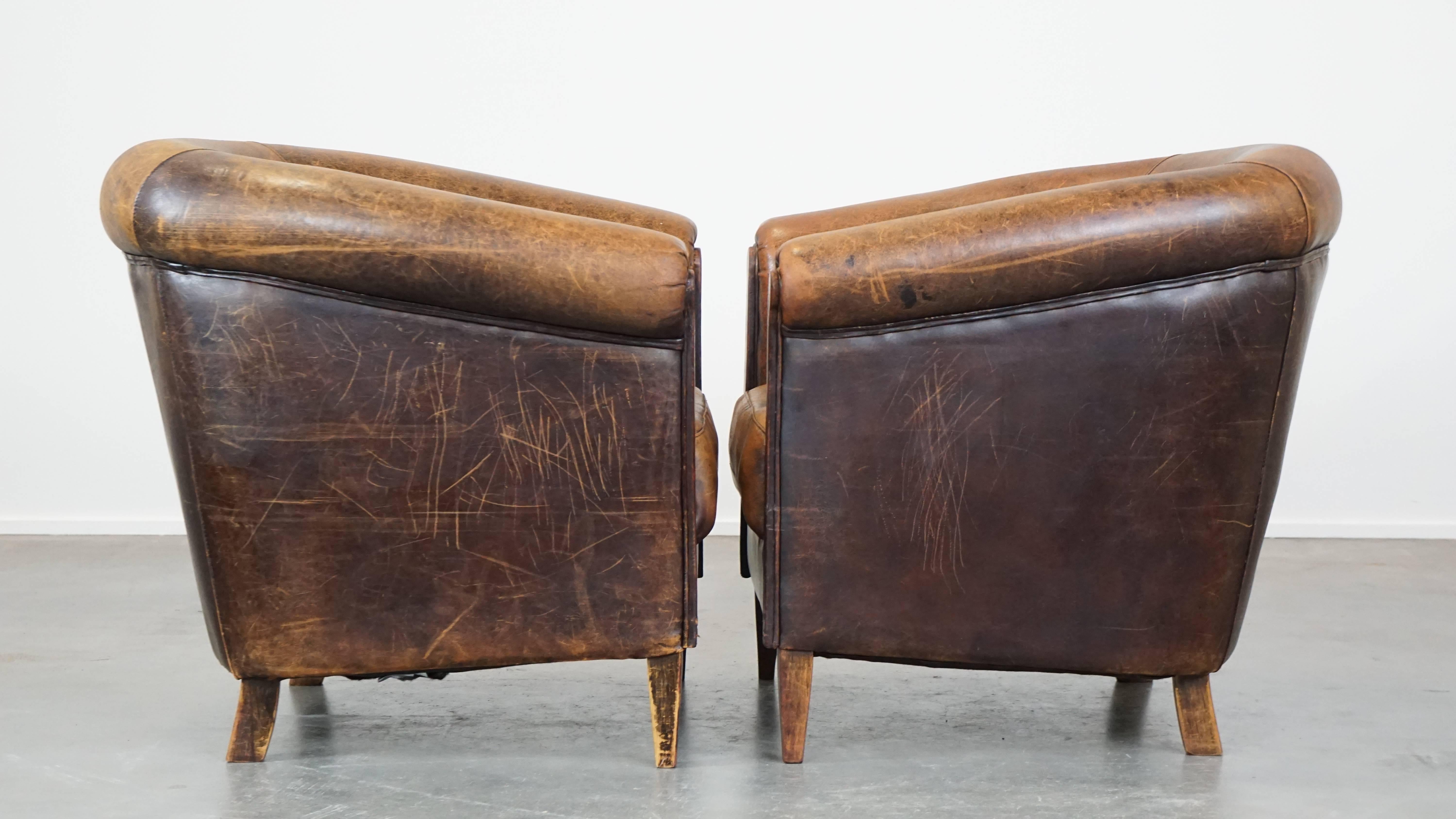 Cet étonnant ensemble de 2 fauteuils club vintage en cuir de mouton est plein de caractère et attire vraiment l'attention. Leur patine et leur combinaison unique de couleurs leur confèrent un aspect usé et robuste. Ces fauteuils club n'ont pas