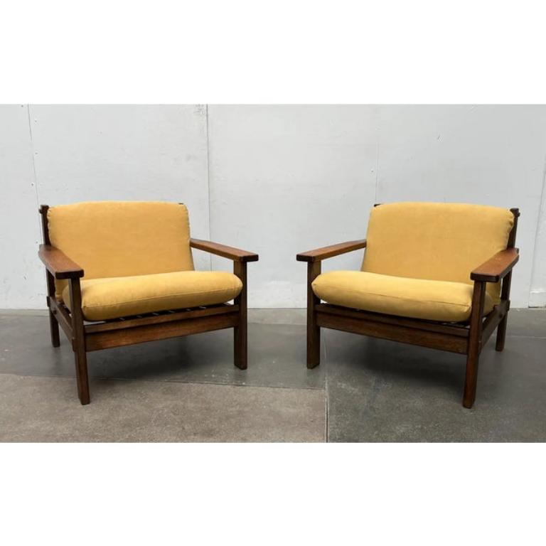 Two impressive mid-century armchairs with yellow upholstery.

The design impresses with its brutalist honesty and high-quality workmanship and materials. The frame is made up of solid wooden elements into which straps are stretched. The construction