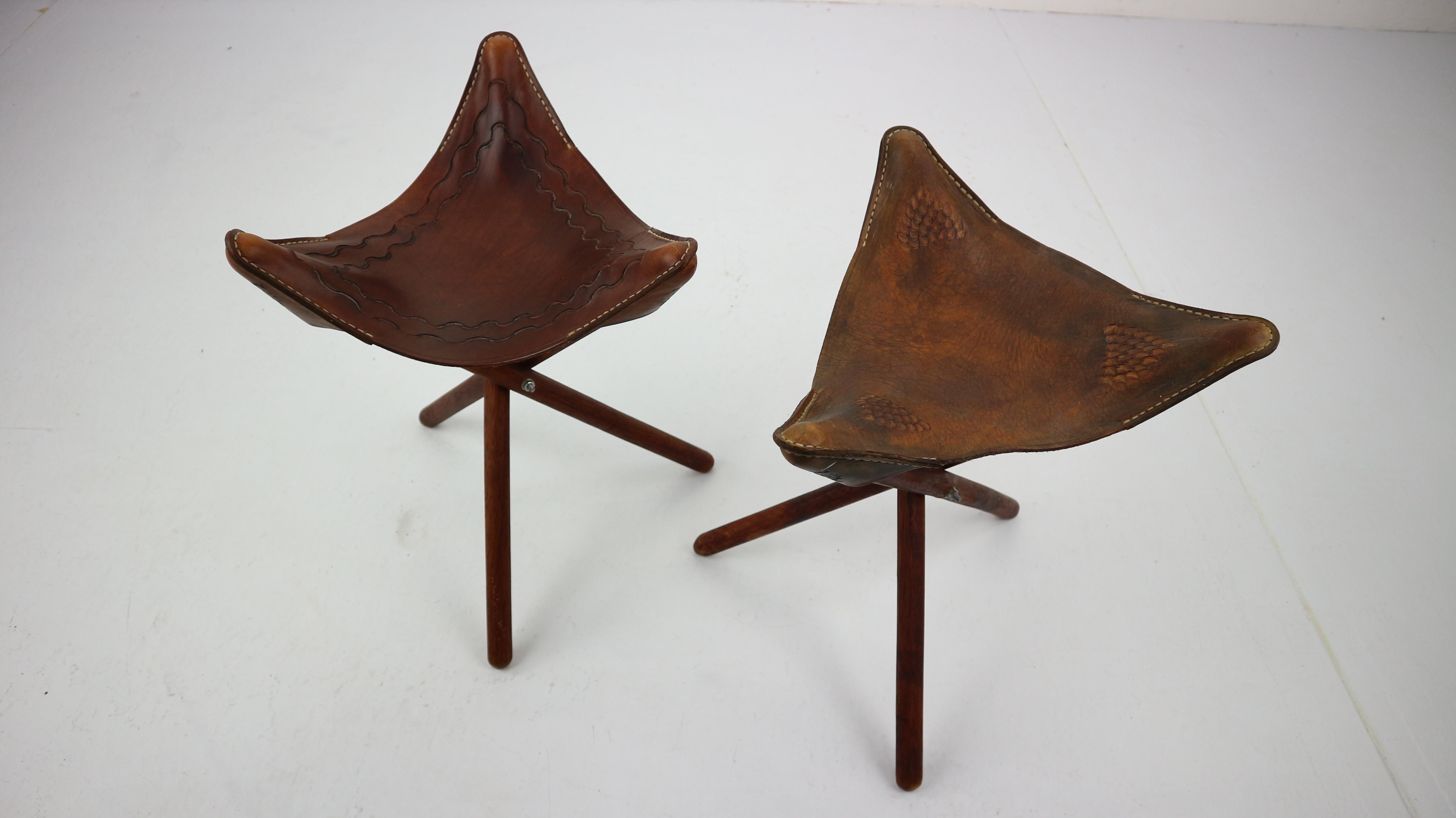 A set of two stylish traveling stools with original leather seat on mahogany tripod frame folding to a stick. Original seating is made from the high quality leather and hand tooled with an ornaments. 
Tripod legs are easily folded. 
Used