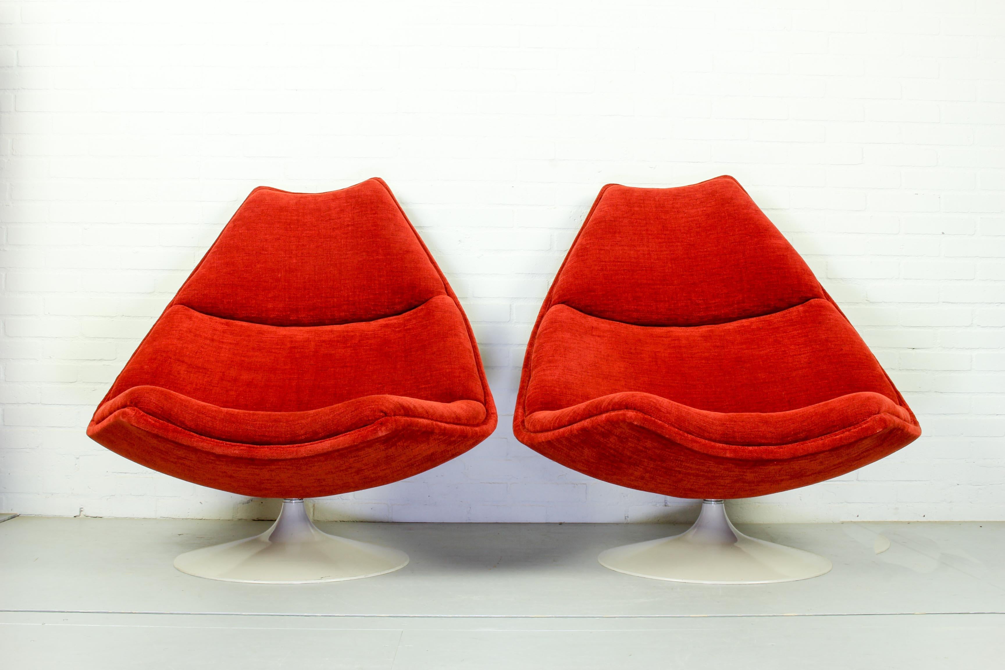 This set of 2 midcentury swivel lounge chairs with futuristic shape and tulip shaped plastic base was designed for Artifort. The set has been reupholstered in 2016 with a beautiful orange-red fabric and shows minor traces of use.