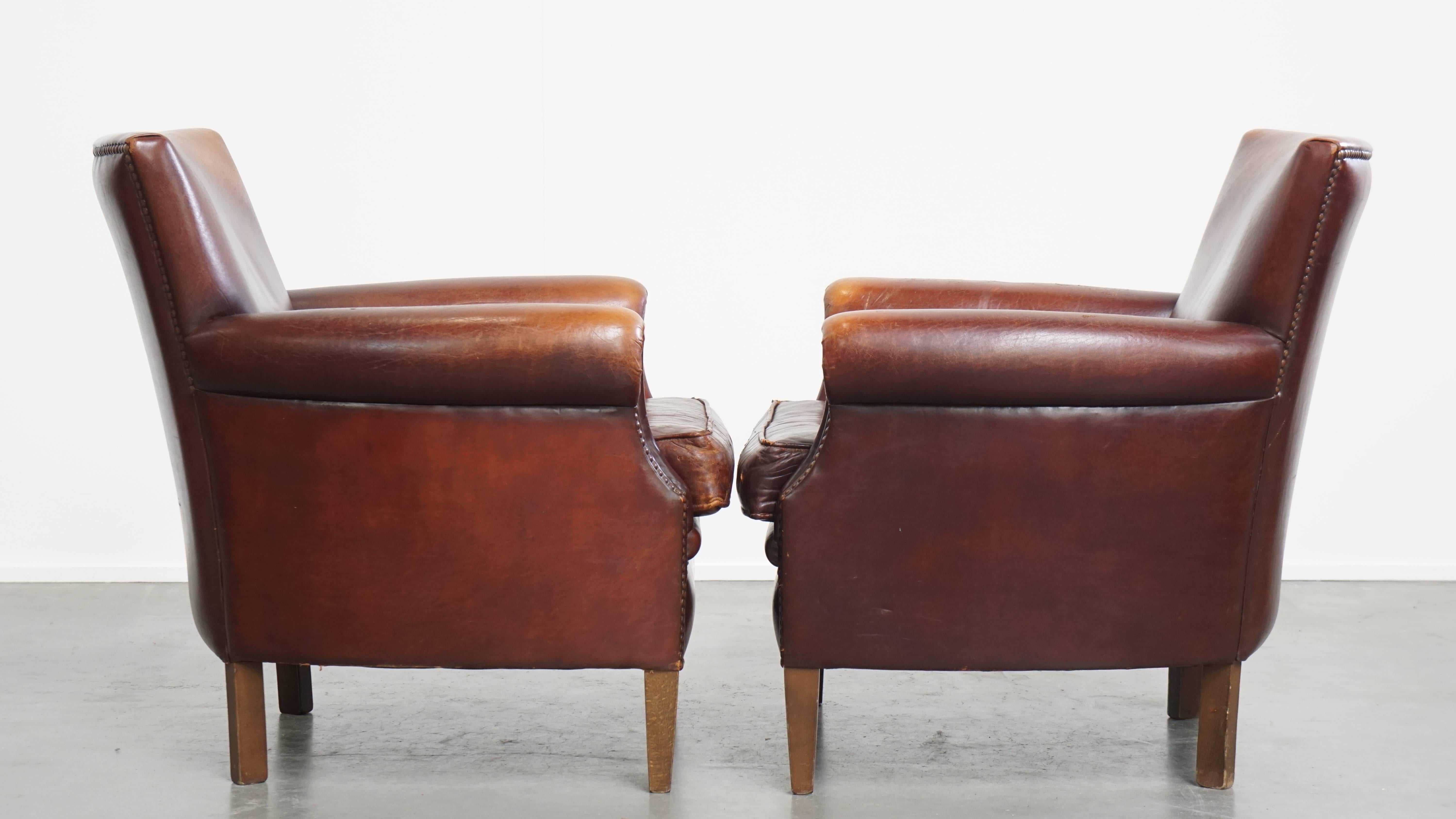 Offered here is this characterful set of 2 vintage sheepskin leather armchairs with warm tones and a beautiful patina. Over the years, this charming set of 2 vintage leather armchairs has developed a wonderful patina. Their warm and inviting colors