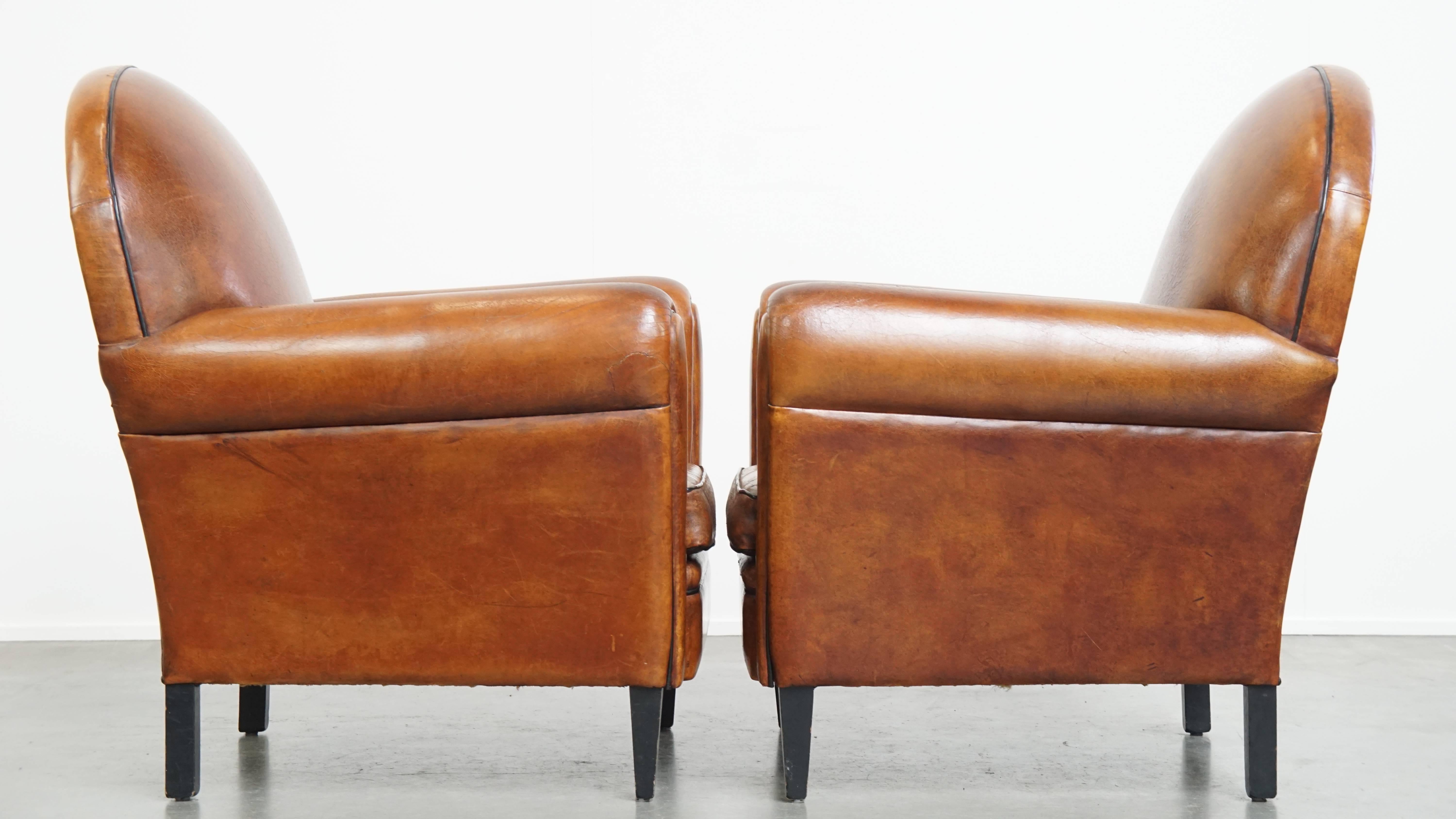 Offered is this set of two bold vintage sheepskin leather Art Deco style design armchairs. 

Over the years, this stunning pair of Art Deco armchairs has developed a beautiful patina and a characterful vintage appearance. They feature refined