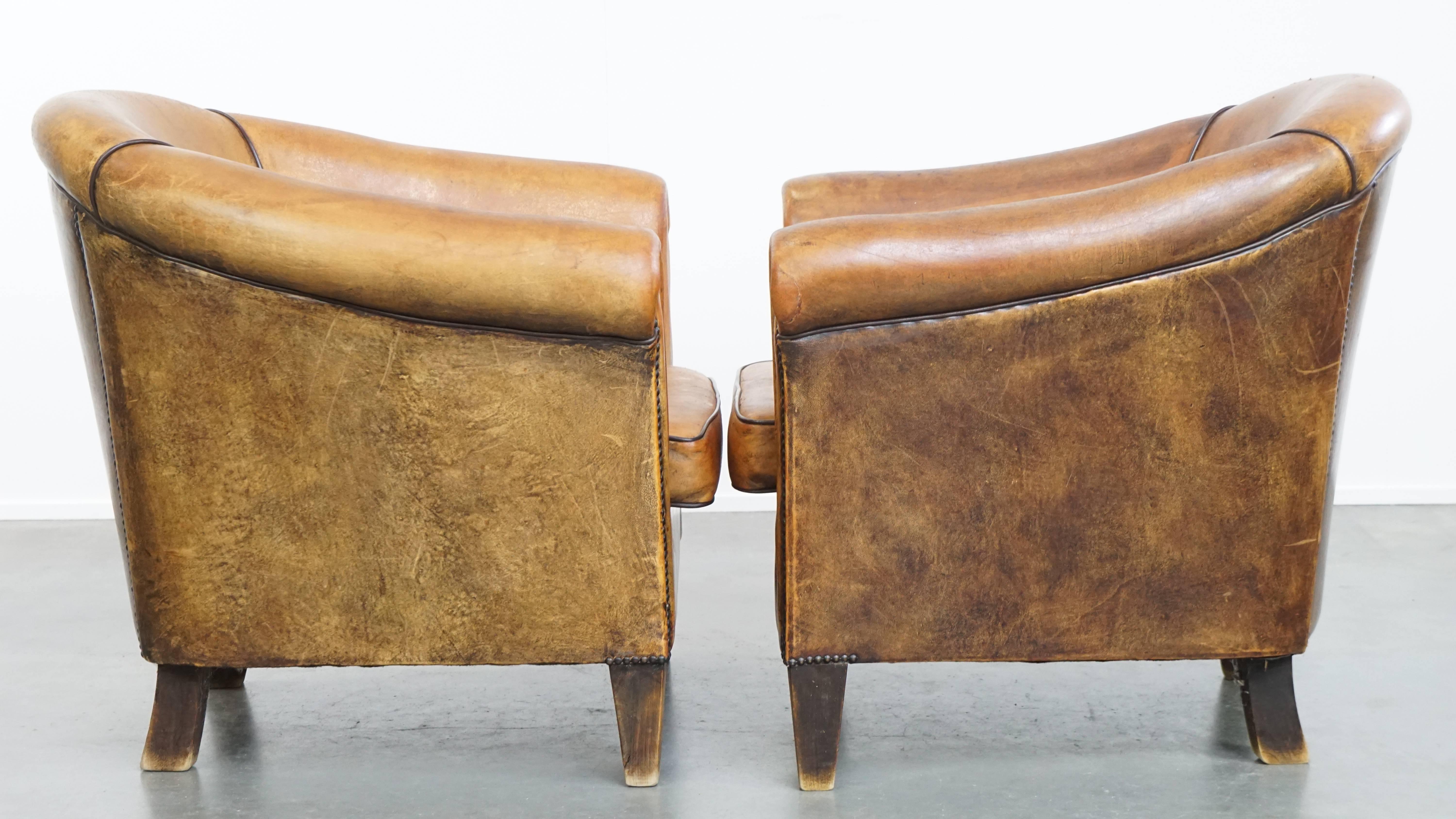 Offered here is this characterful set of 2 robust vintage sheepskin leather club armchairs with a beautiful patina. 

This set features removable seat cushions and offers pleasantly firm seating comfort. The armchairs are finely finished with