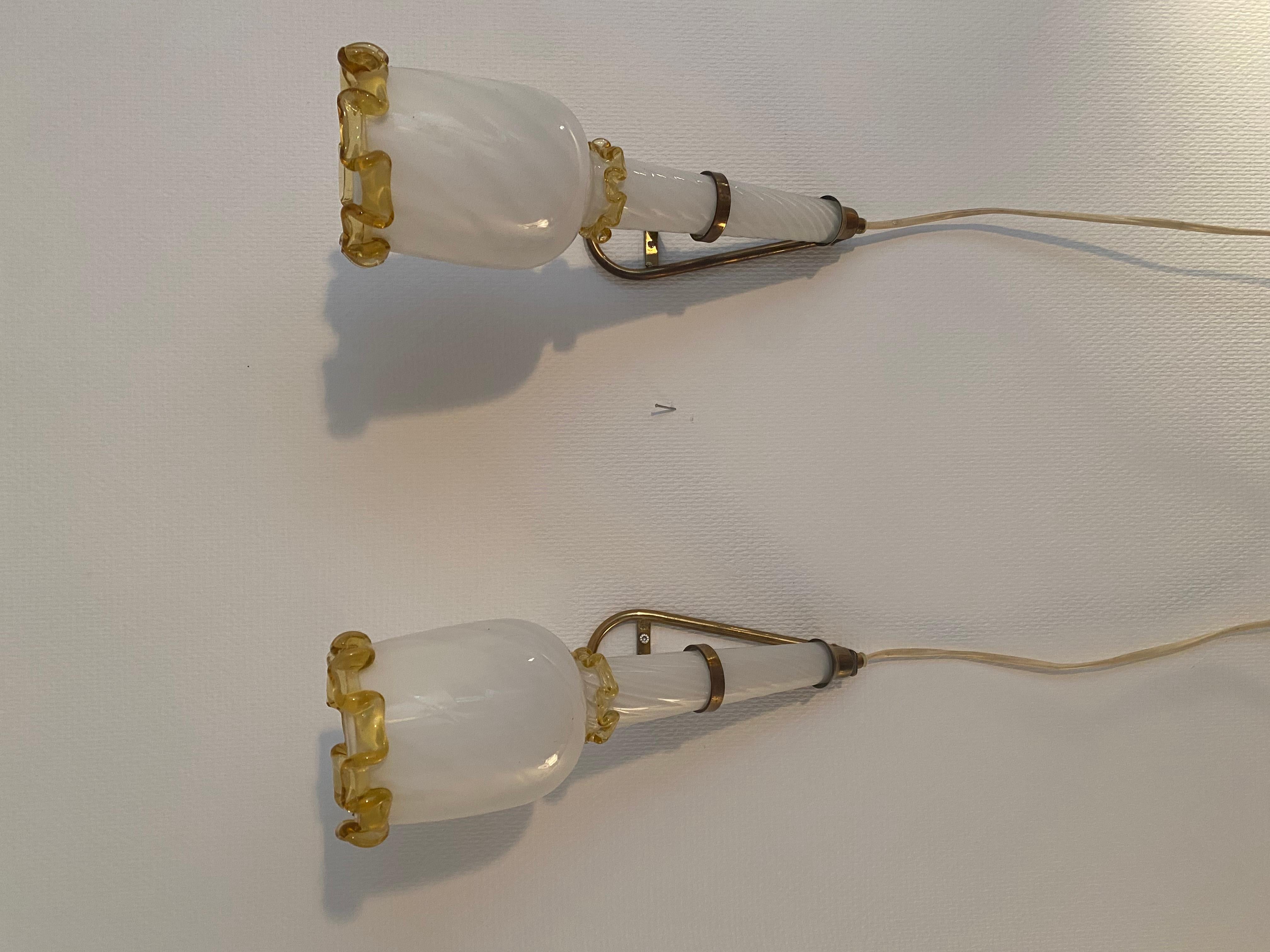 Set aus 2 Wandleuchten von Venini in Form von Fackeln. Opalglas und Messinghalter. Ursprüngliche Verkabelung. Das Design wird Fulvio Bianconi zugeschrieben. Höhe: 38 cm Tiefe (ab Wand): 25 cm Breite: 10 cm

Diese Wandleuchten in Form von Fackeln