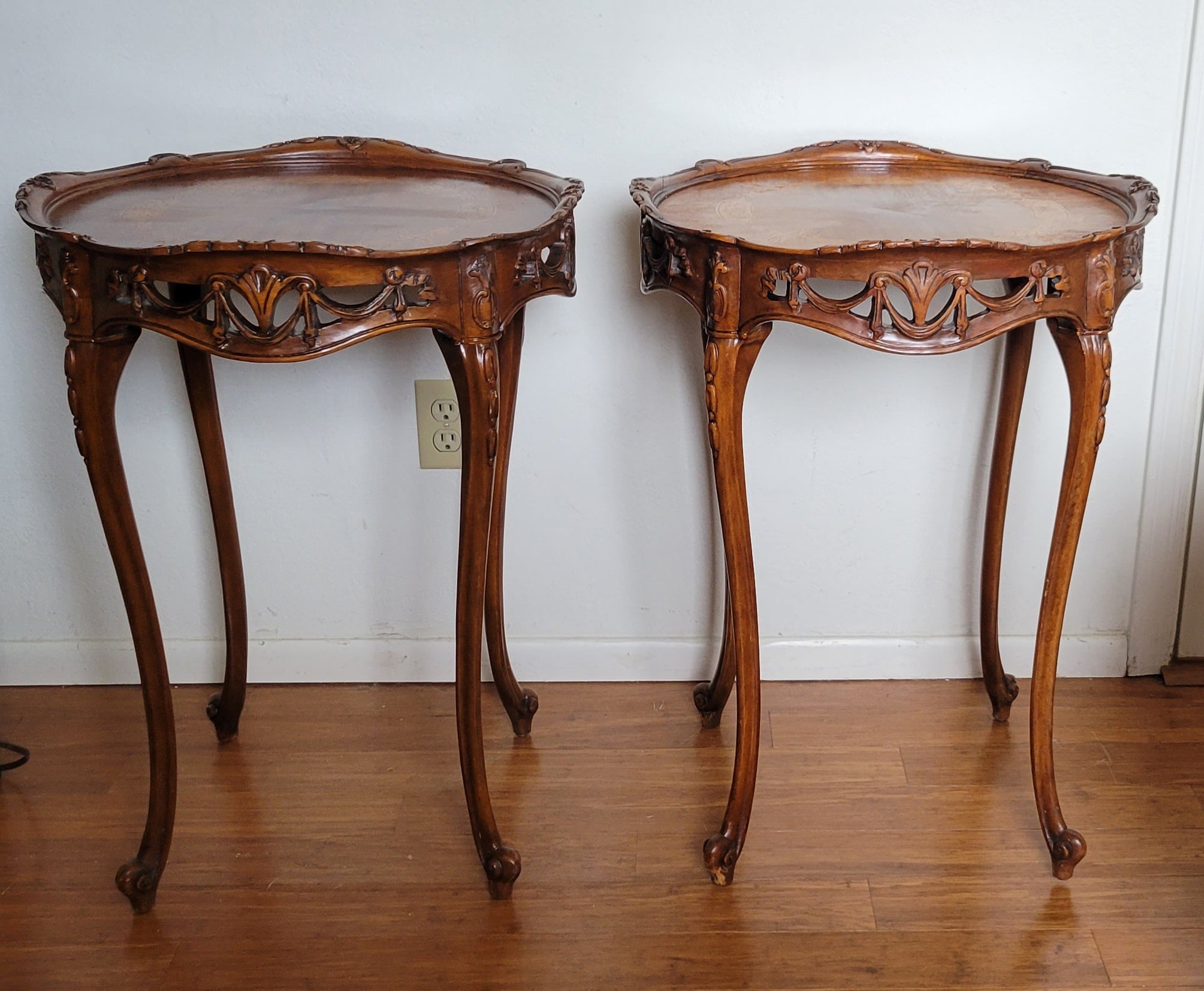 A set of (2) hand-carved walnut side tables with inlays and a delicate carvings around the cirumference. 
The tops of both tables are protected with polished edge glass. 
The inlays have some age-related wear. 
Both tables are very sturdy.

Please