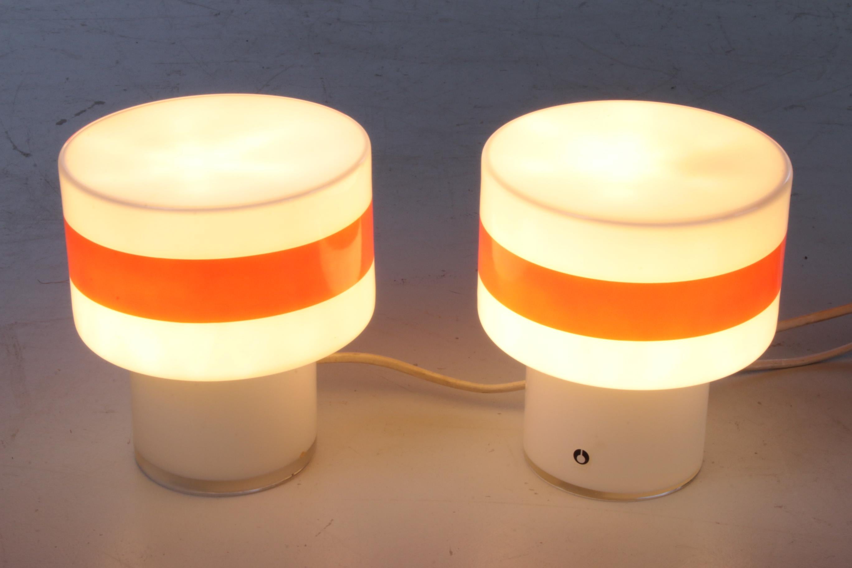 This is a set of table lamps made of white glass with an interesting orange stripe that gives the lamp its unique look.

The designer of the lamps is unknown to us, but we know that they were produced by Pukeberg in Sweden, around the