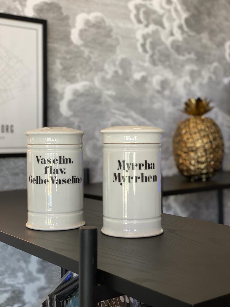 These 2 porcelain pharmacy vessels are from Germany, circa 1880. The porcelain vessels with lids are labeled with the commercial serif typography of the time. One of them has the inscription 