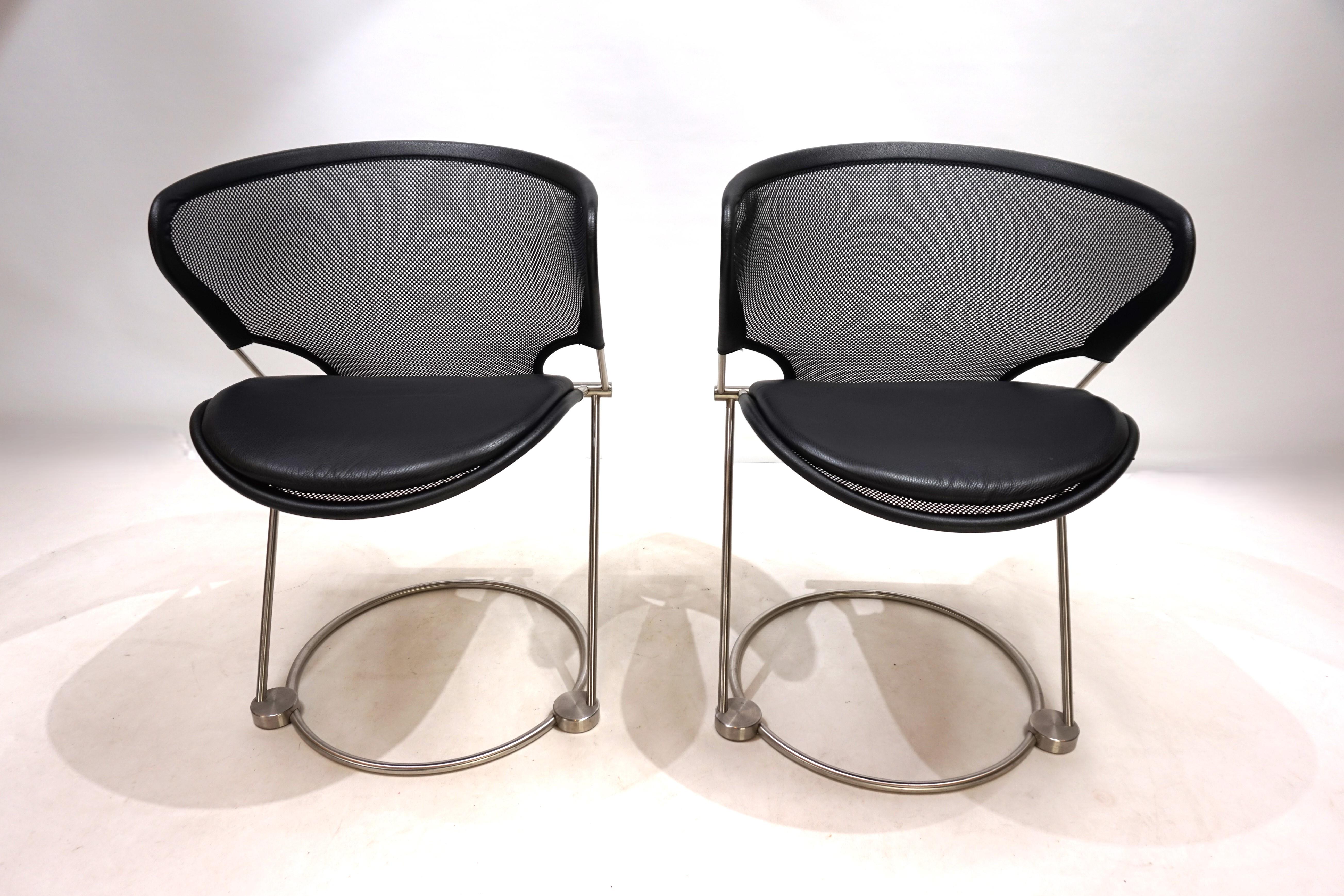 Les deux chaises Condit sont en excellent état, comme neuves. Le cadre solide en acier inoxydable s'harmonise parfaitement avec la maille polyester noire très tendue des assises et des dossiers. La maille est bordée de lanières de cuir noir aux