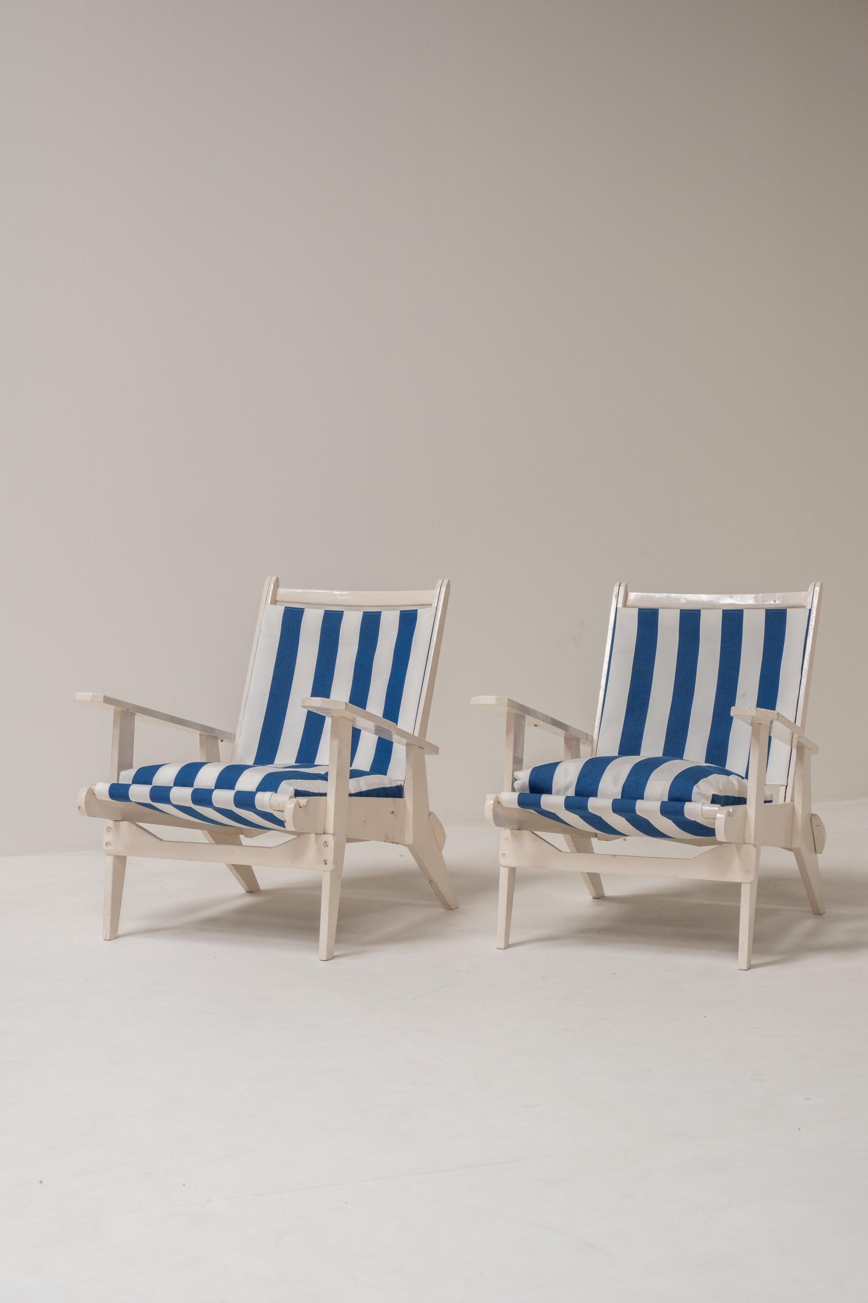 Coppia di sedie da salotto in legno in classico stile Costa Azzurra, appena rivestite con un tessuto a righe bianche e blu. Il design è caratterizzato da ampi e comodi braccioli, gambe elegantemente angolate e una silhouette rilassata, che bilancia