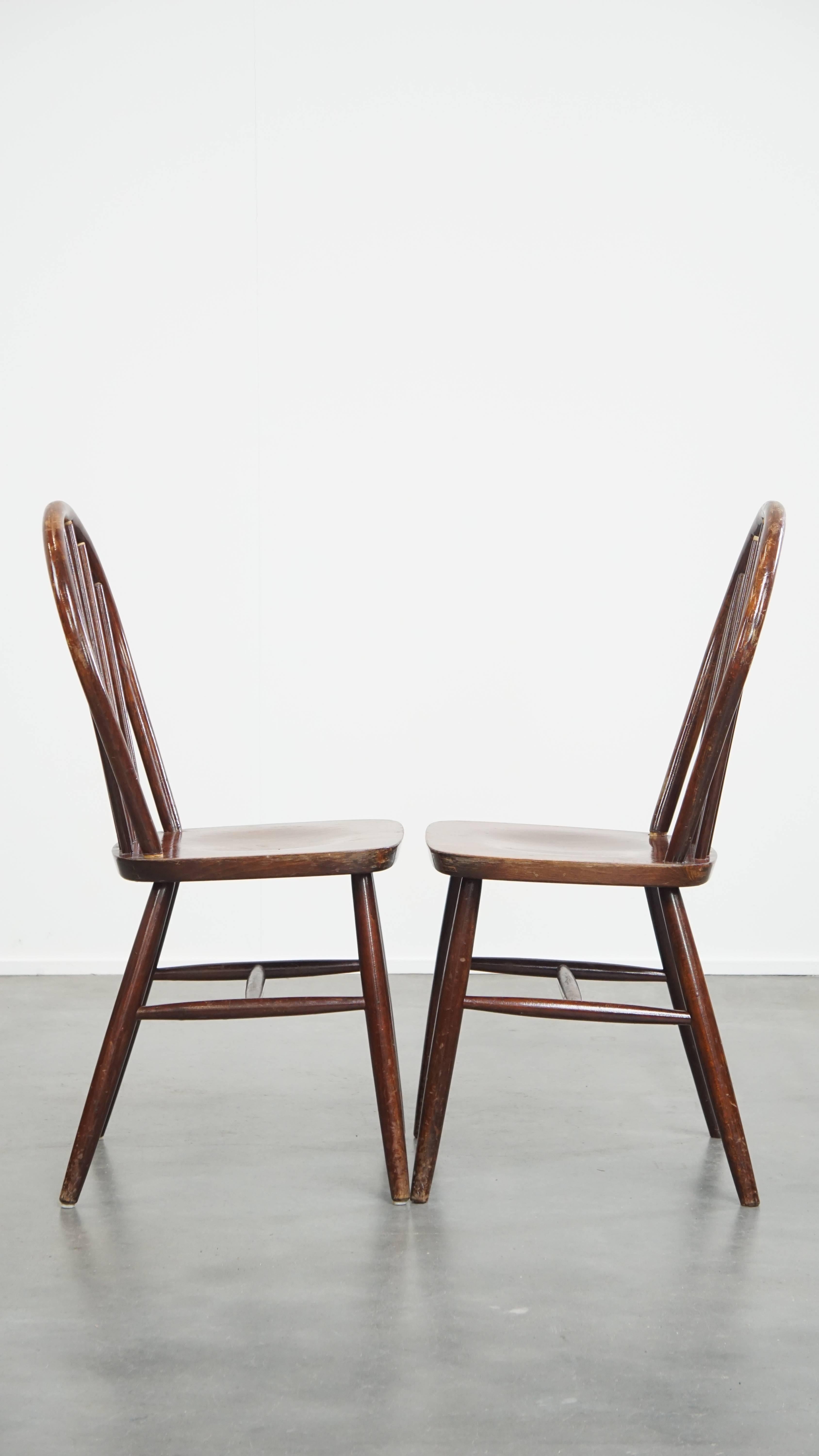 Offered here is this set of 2 wooden vintage spindle Windsor chairs from the 1970s in English style. These wonderful vintage Windsor chairs from the 1970s are not only perfectly suited for use in a home environment, but they also work beautifully in