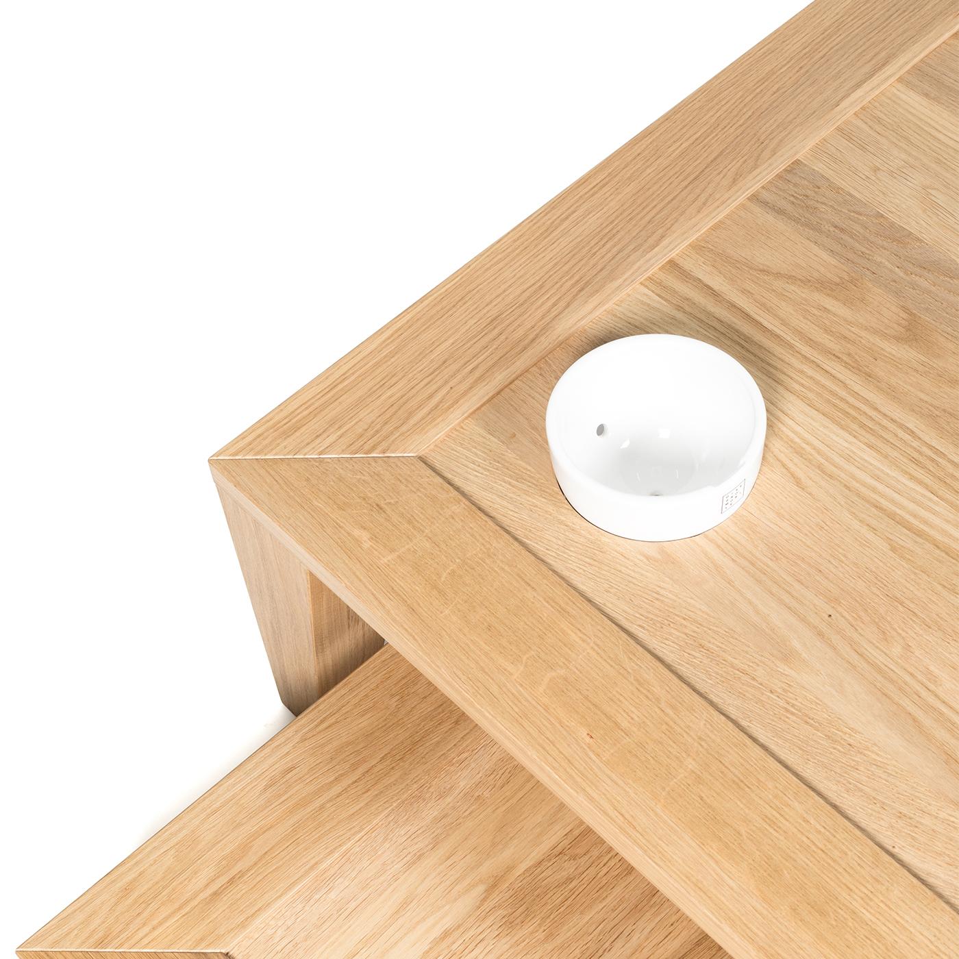 This set of coffee tables is perfect for any modern office or living space. The table structures and legs are in solid oak coated in a water-based varnish for a clean, natural look. A small white ceramic bowl serves as a valet tray in the corner of