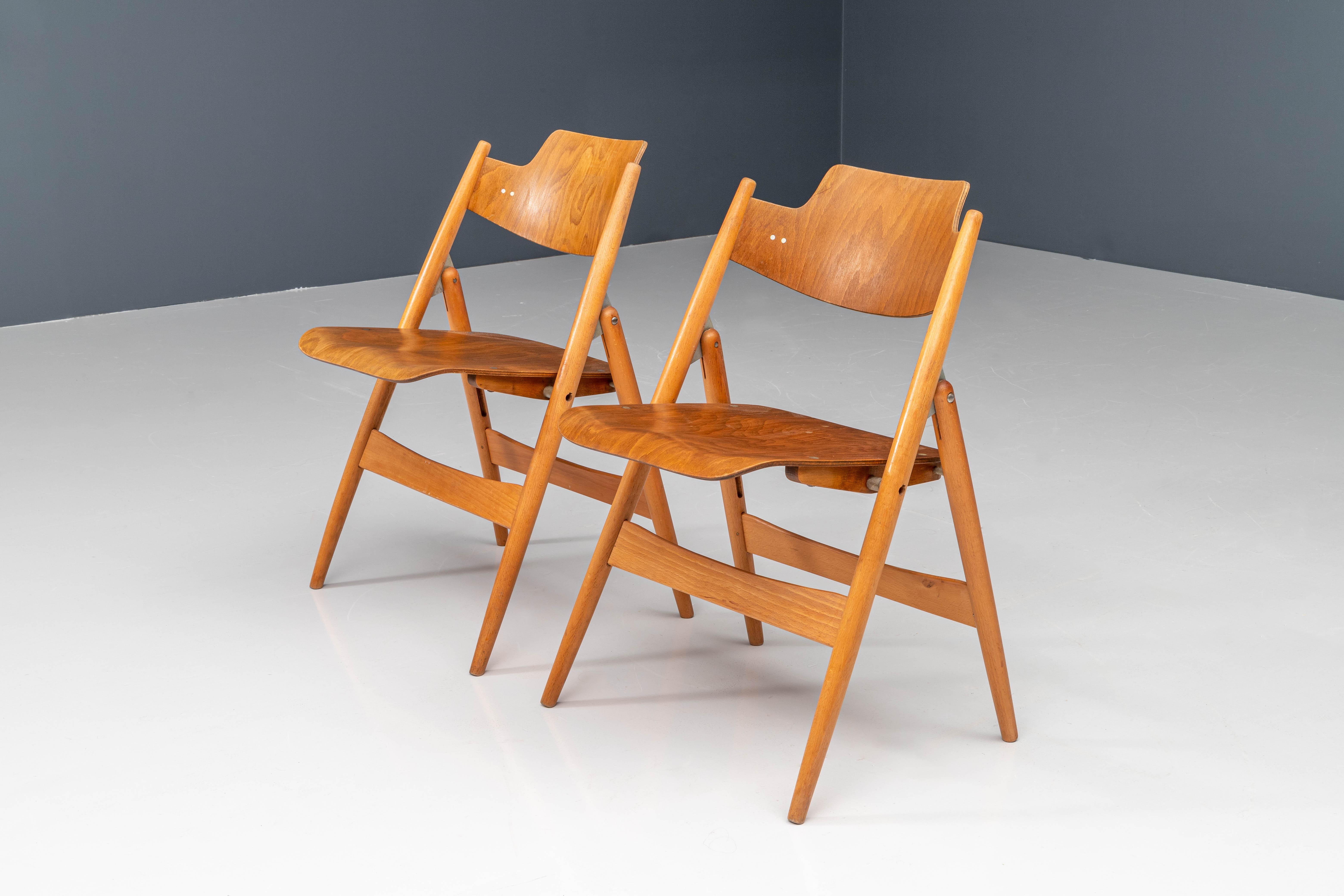 Diese Klappstühle, Modell SE18, wurden 1952 vom deutschen Architekten Egon Eiermann für Wilde & Spieth entworfen. Das Gestell besteht aus Buchenholz, während Sitz und Rückenlehne aus Formsperrholz mit Buchenfurnier gefertigt sind. Der Stuhl ist