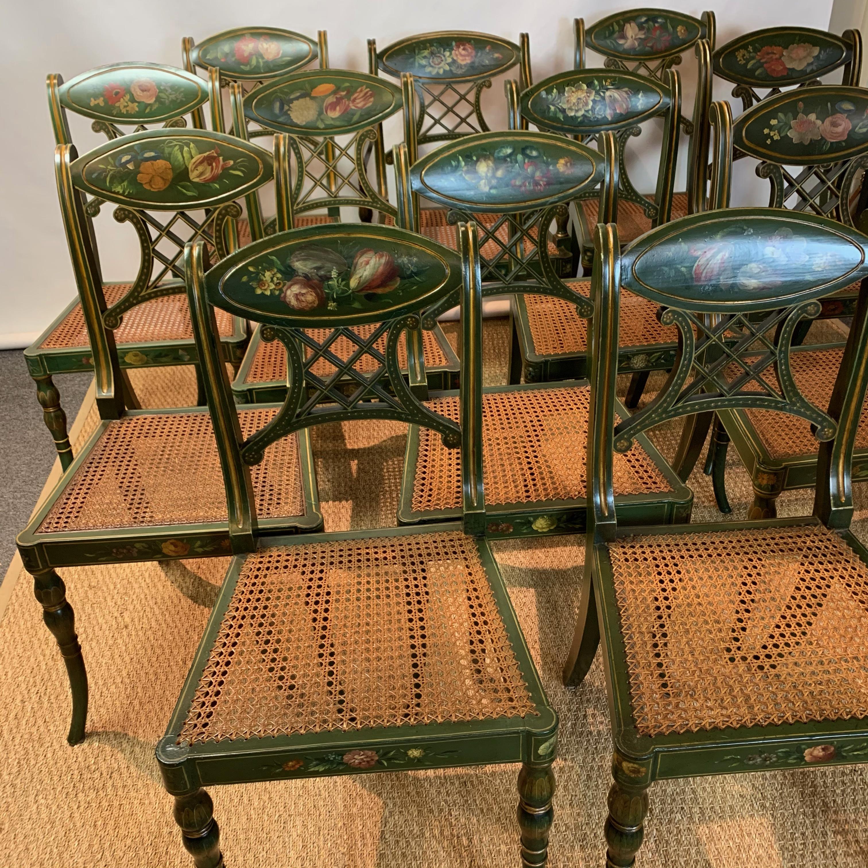 An exceptionally large set of 22 Regency style moss green dining chairs comprising 2 armchairs and 20 sides each elaborately decorated with flowers and gilt accents with cane seats and custom silk covered cushions.